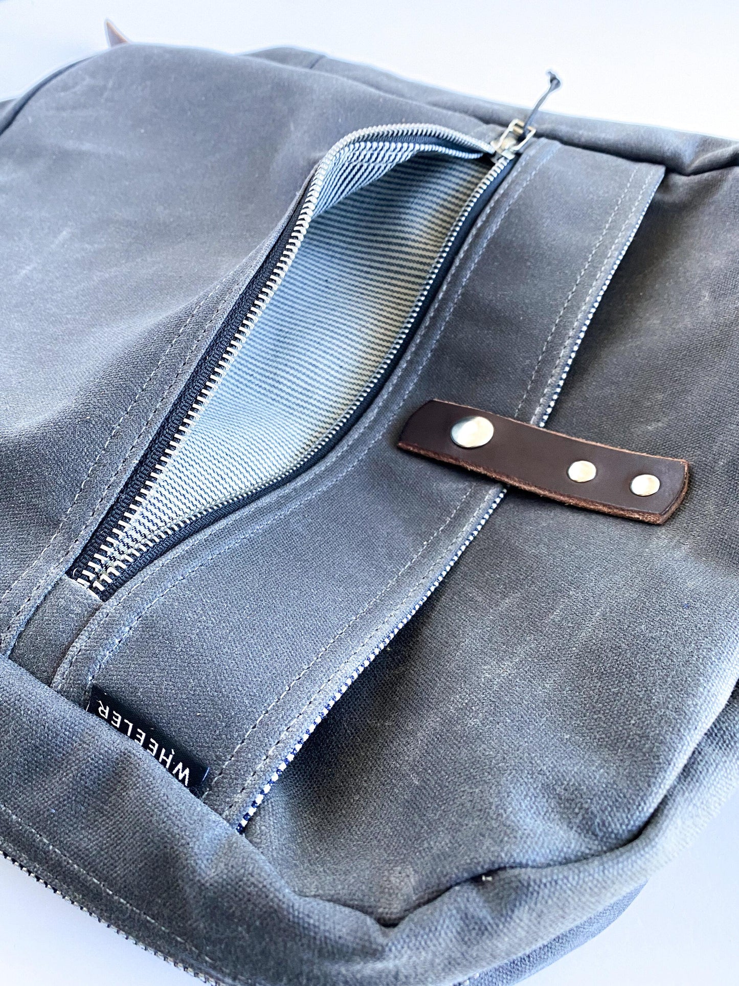 Waxed cotton canvas backpack zipper pocket & snap detail. 