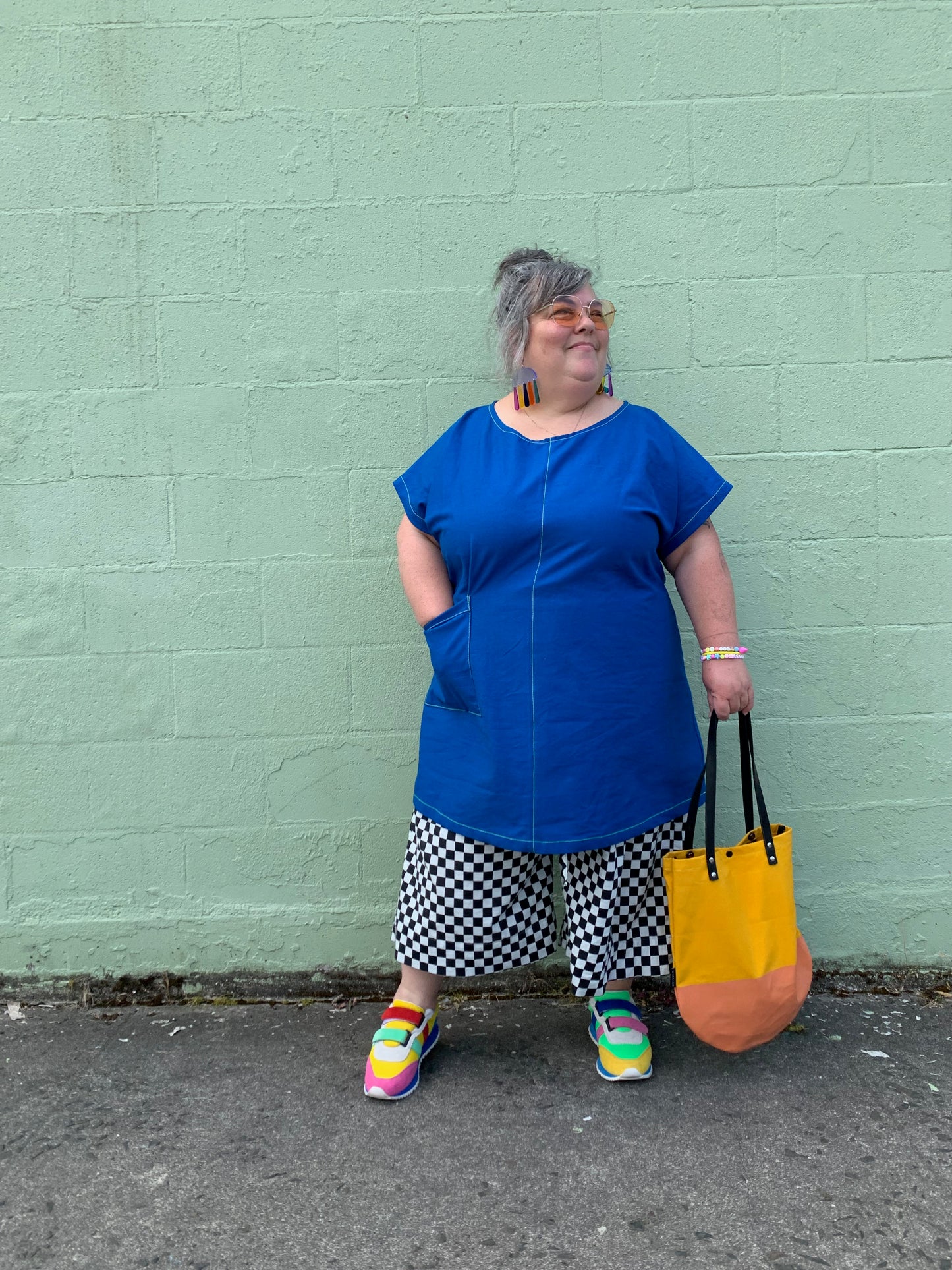 Brightest blue tunic with neon yellow/green topstitching and one big pocket. 55% linen, 45% cotton, medium weight. Model is holding yellow round bottom bag.