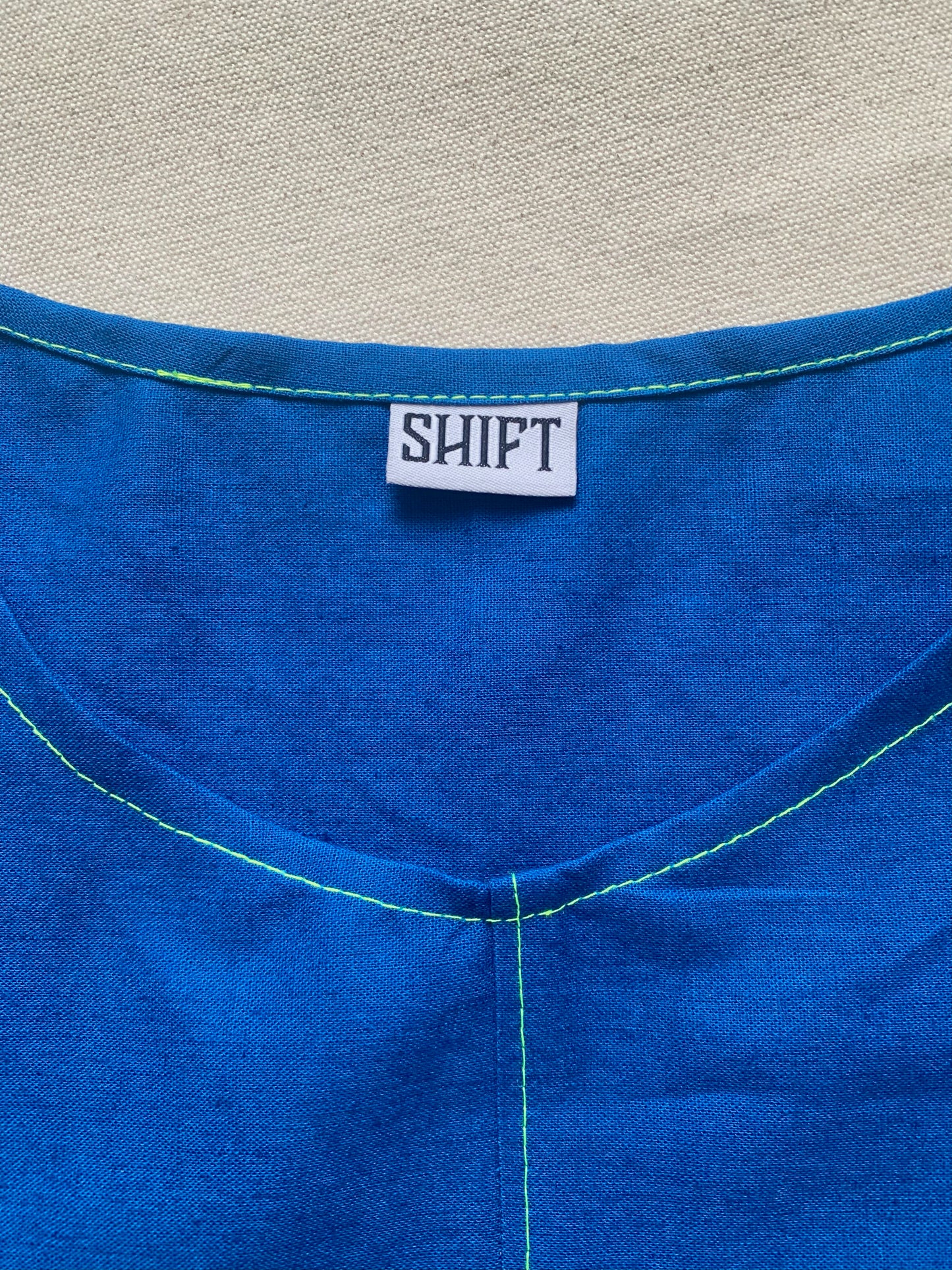 Brightest blue tunic with neon yellow/green topstitching and one big pocket. 55% linen, 45% cotton, medium weight.