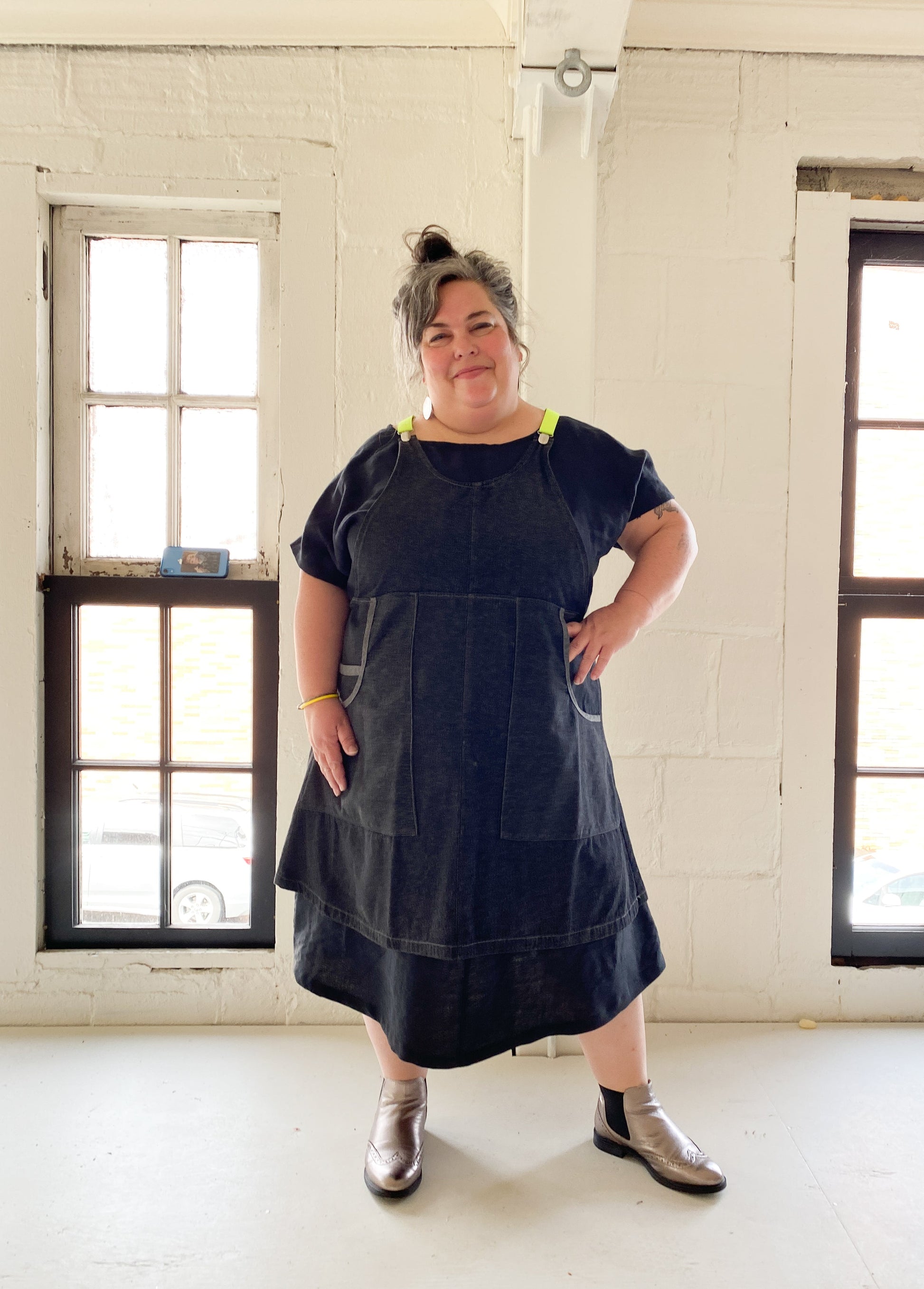 A-line, longer linen dress has two big patch pockets on the front. Modeled with denim suspender dress.