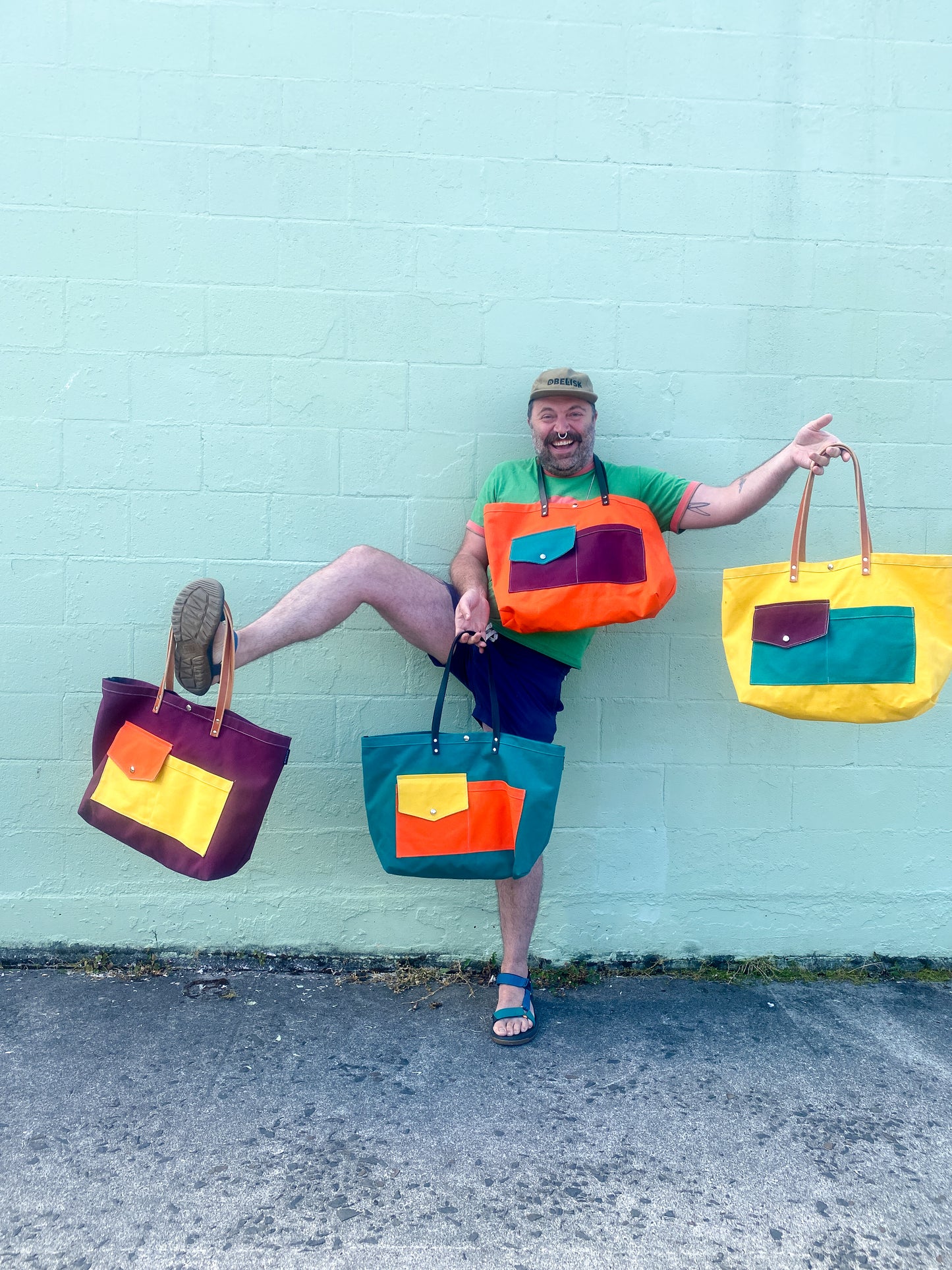 Multi-color (yellow, purple, teal, orange) canvas beach tote with leather straps. Model is holding four different color combinations.