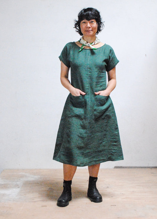 Model with hands in pockets wearing Shift + Wheeler Basic Dress in green linen