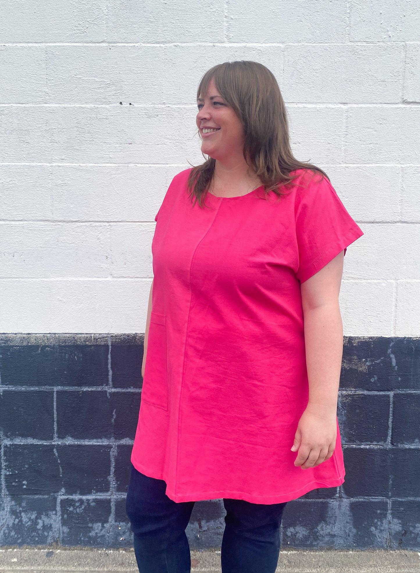 Brightest pink tunic with weirdly satisfying tan topstitching, and one giant pocket. 55% linen, 45% cotton, medium weight. 3/4 angle.