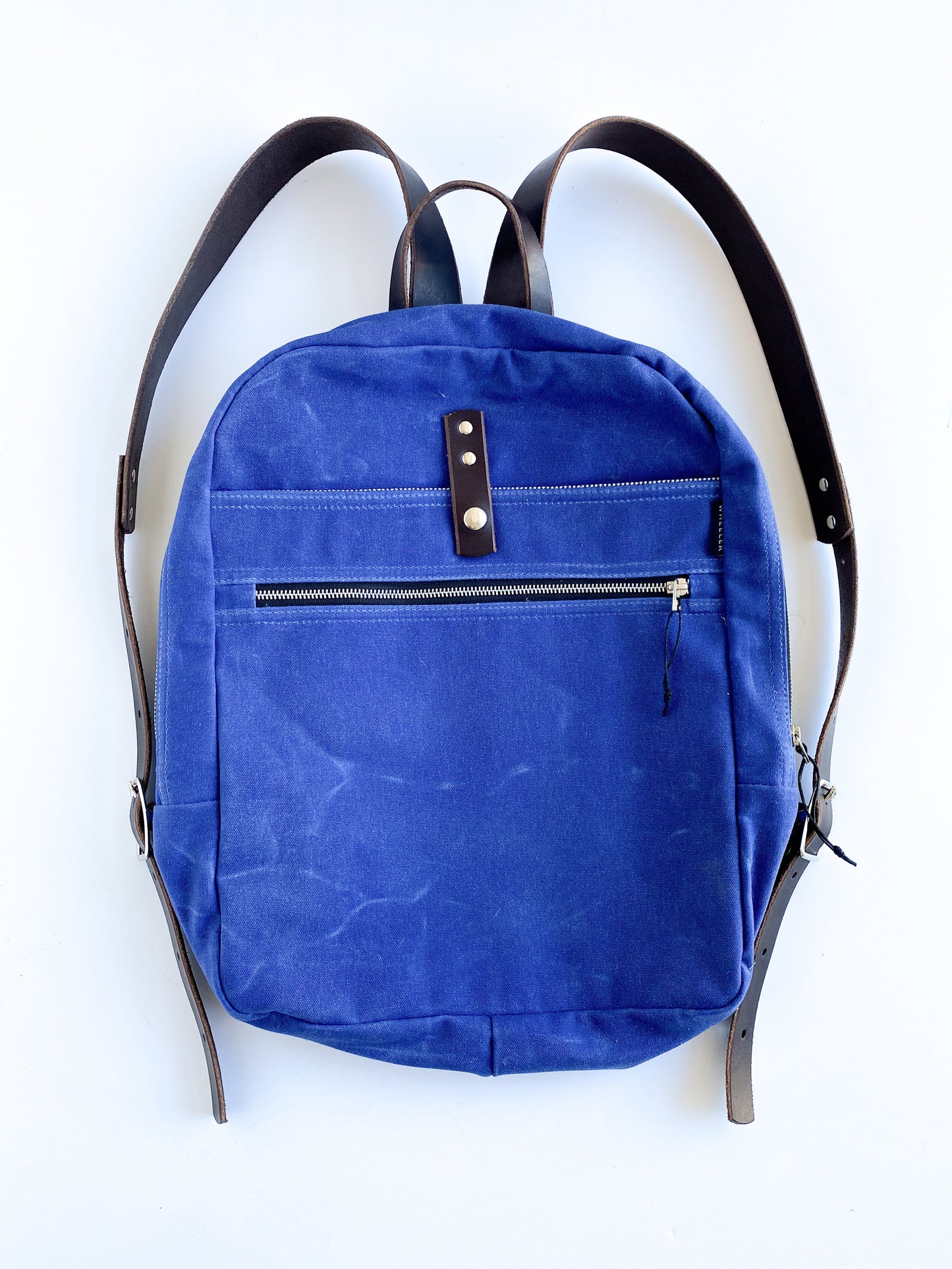 Royal, waxed cotton canvas backpack with brown straps.