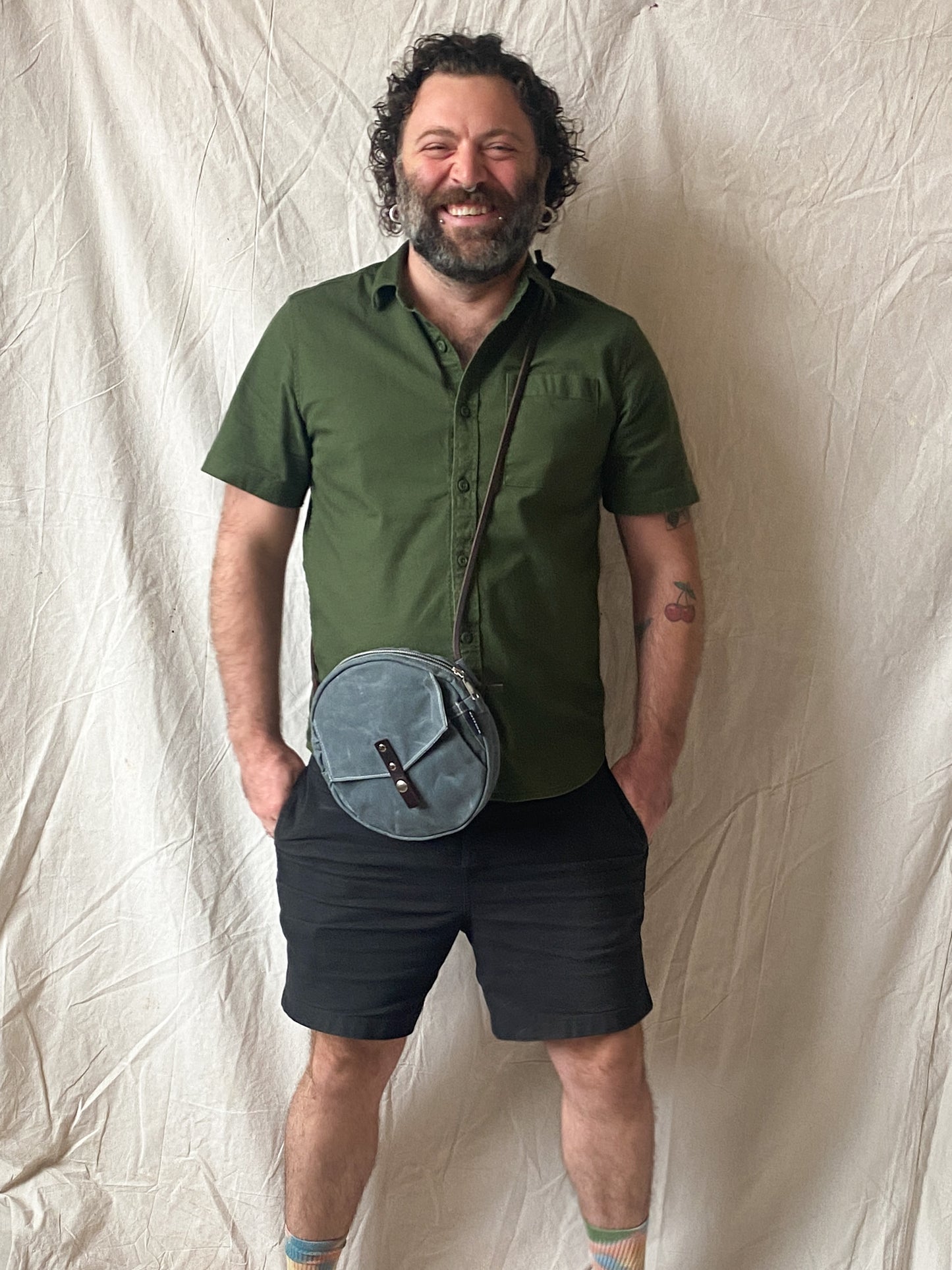 Circle bag with leather straps in slate. Model facing forward.