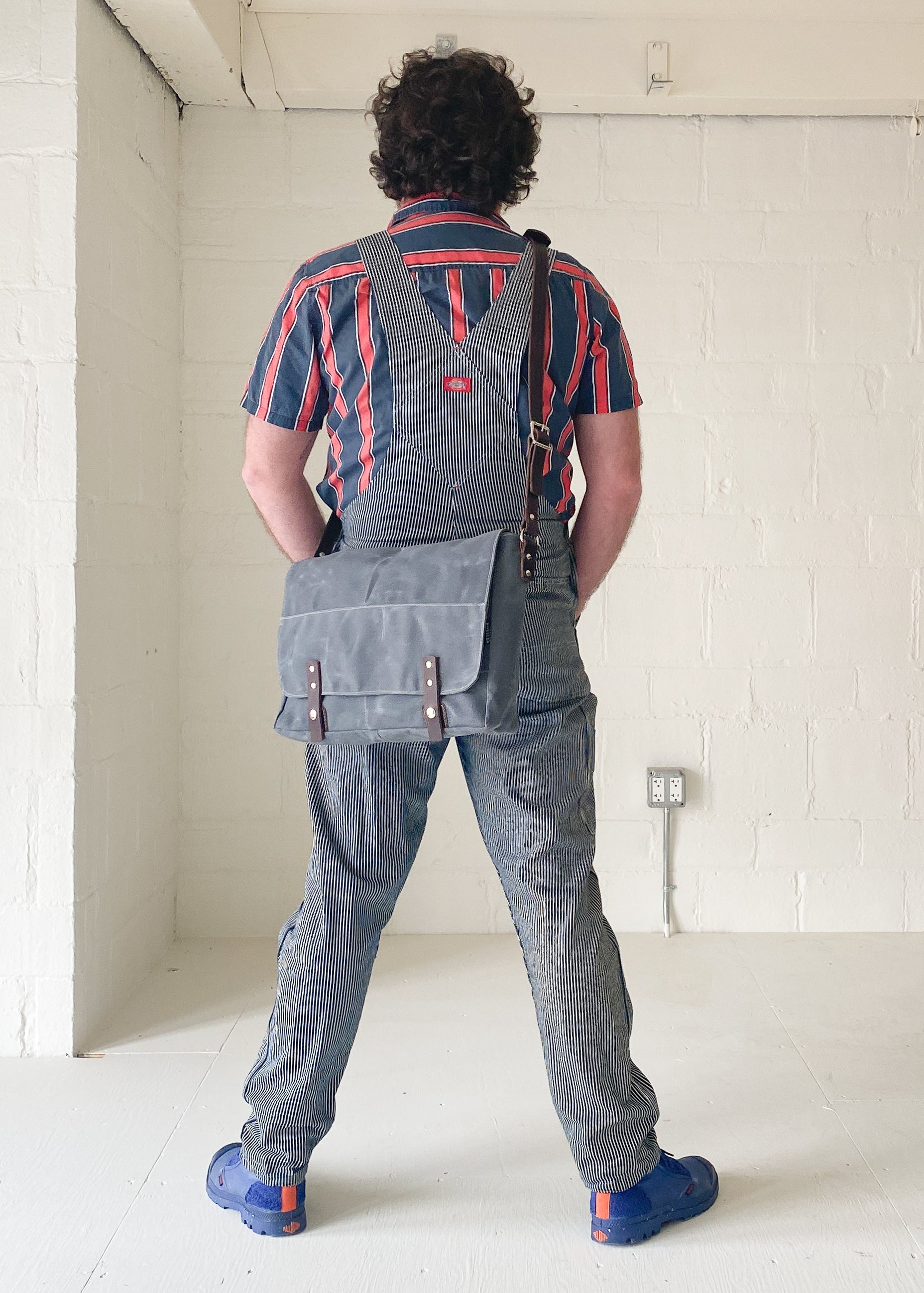 Model wearing Slate, waxed canvas messenger bag.