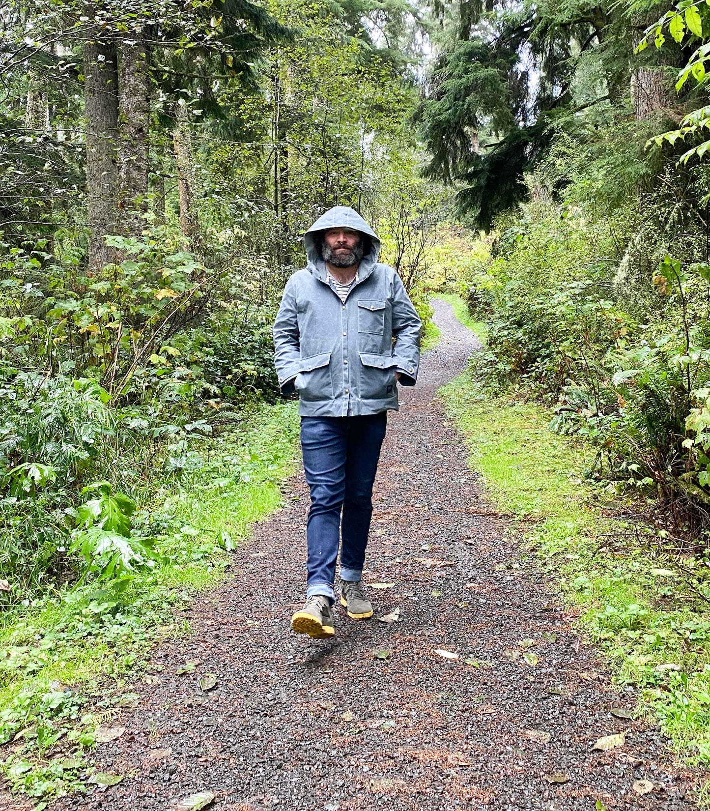 Model wearing Waxed Canvas Raincoat in Slate with hood up.