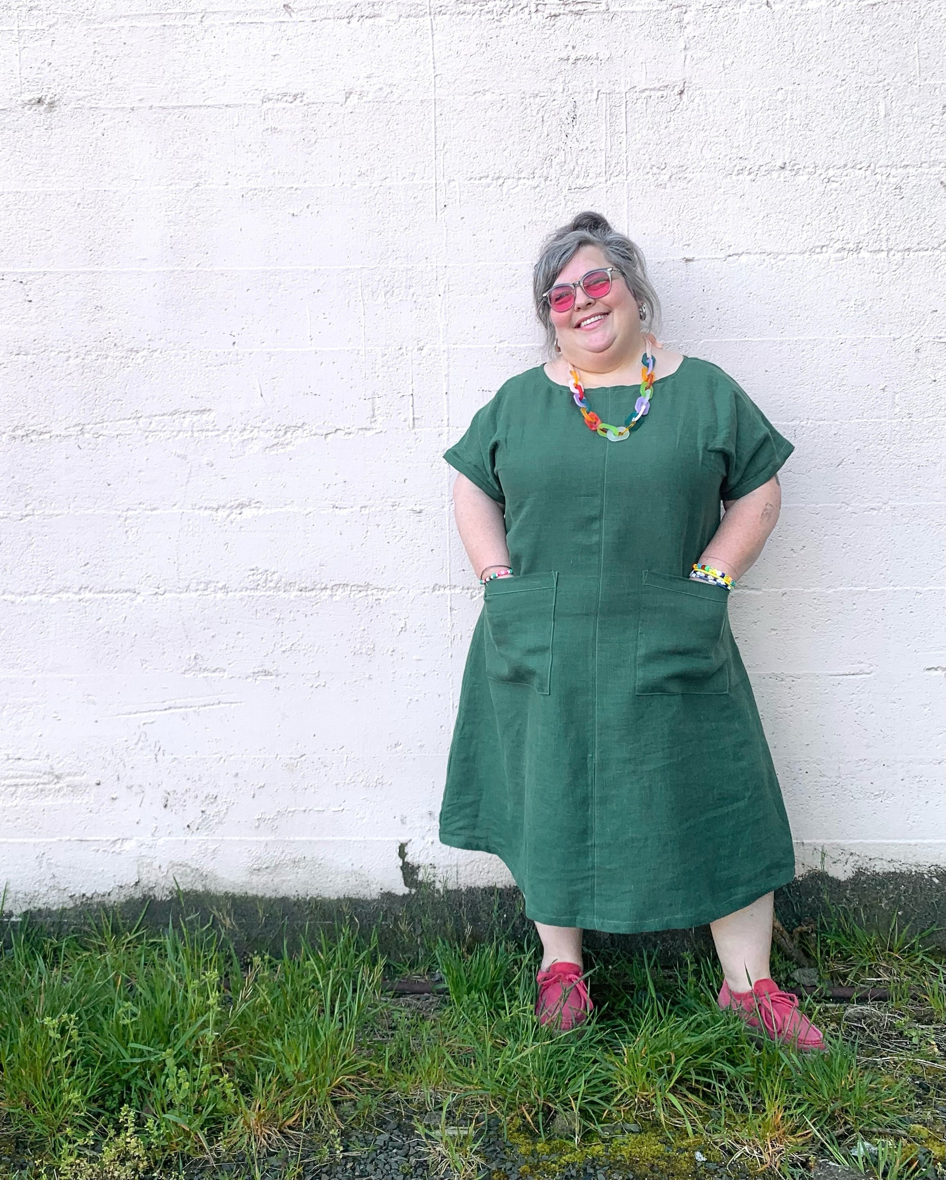 Hands in pockets, leaning against wall. Handmade a-line linen dress. 