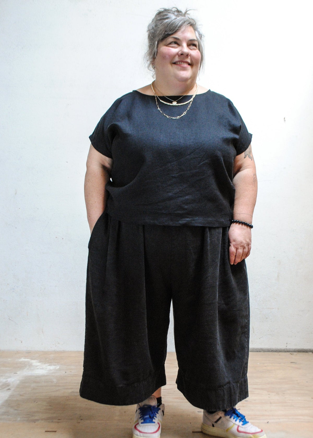 Model wearing Shift + Wheeler handmade black linen/cotton basic top with dark pants and tennis shoes