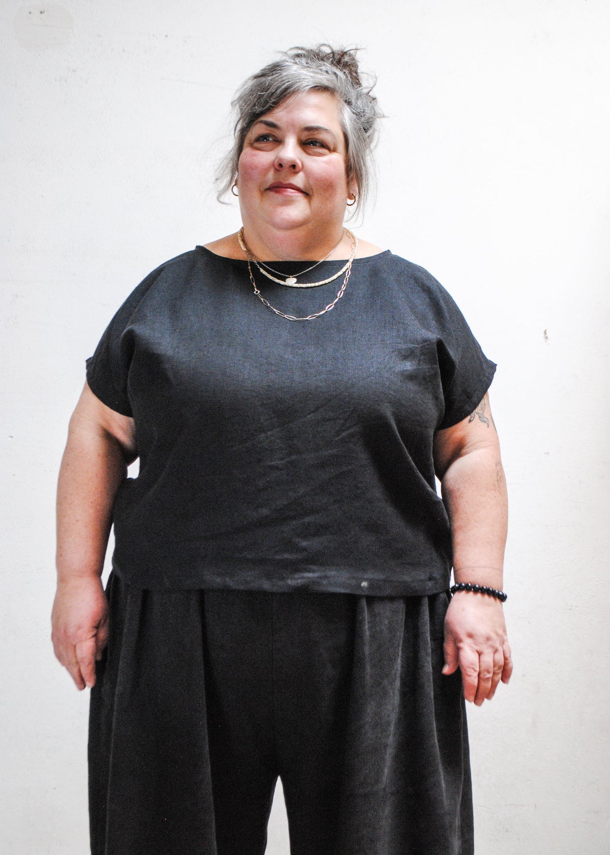 Model wearing Shift + Wheeler handmade black linen/cotton basic top with dark pants