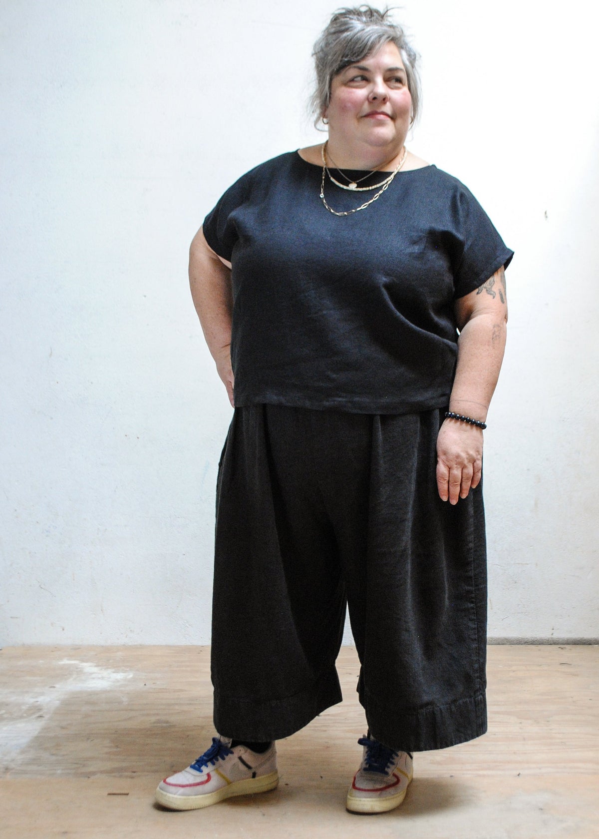 Model wearing Shift + Wheeler handmade black linen/cotton basic top with dark pants and tennis shoes
