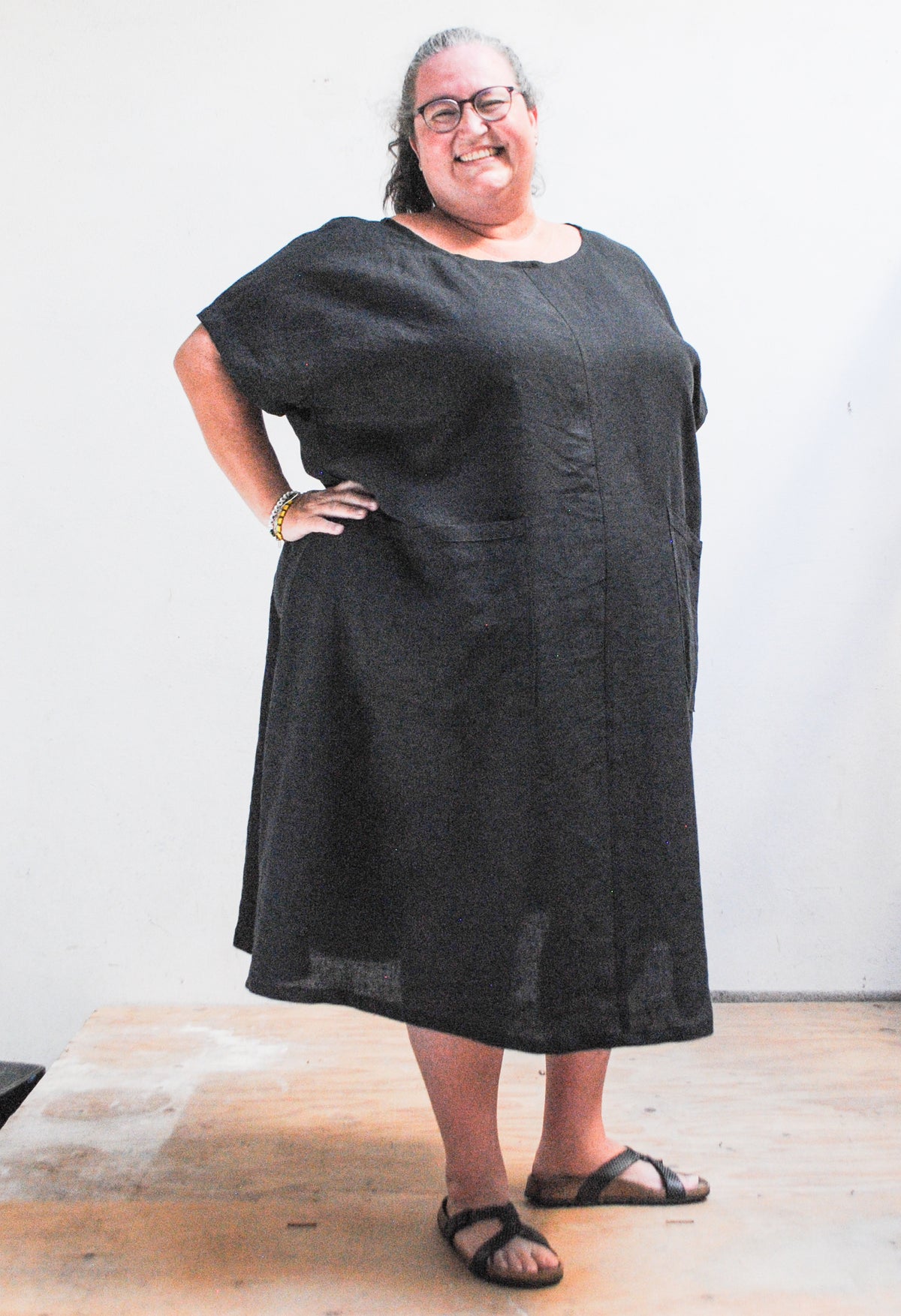 Emily models the Black Linen Basic Dress with hand on her hip. Size 5XL. 