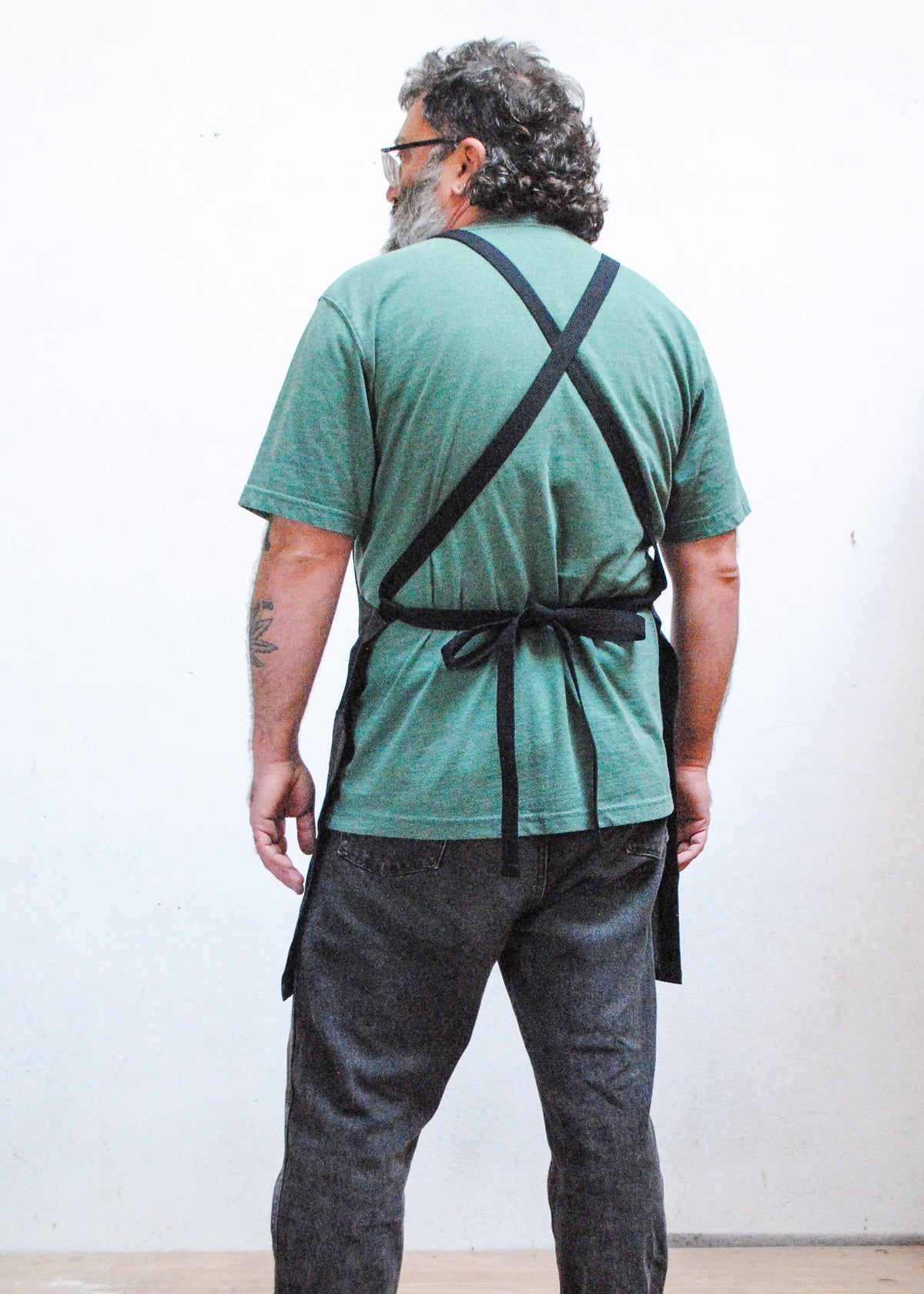Back view of crossback black denim apron on model