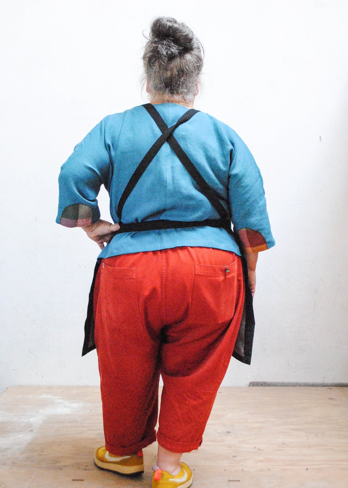 Back view of crossback black denim apron on model