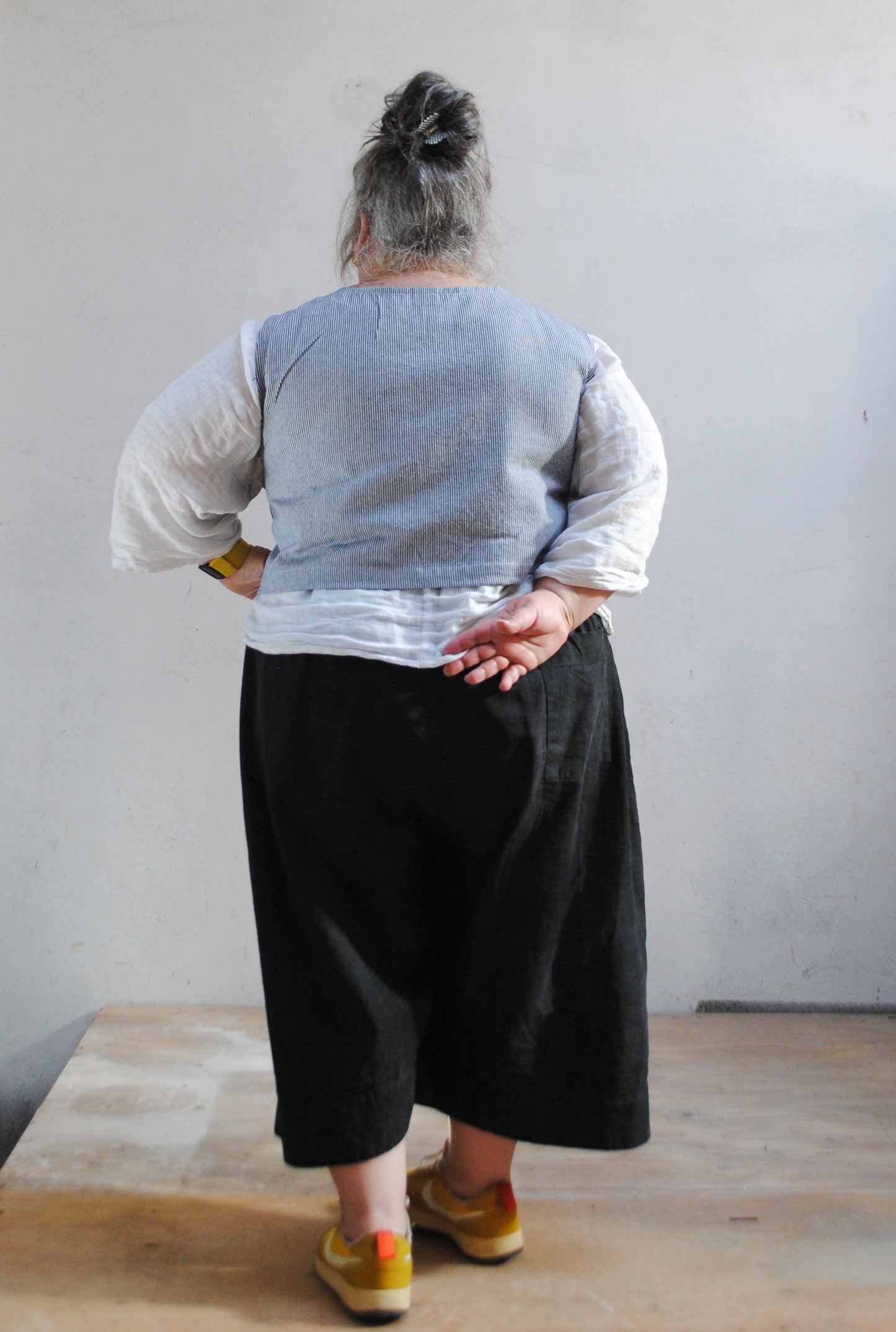 Model wearing crop railroad denim vest in size 2XL with 52" bust. Back view. 