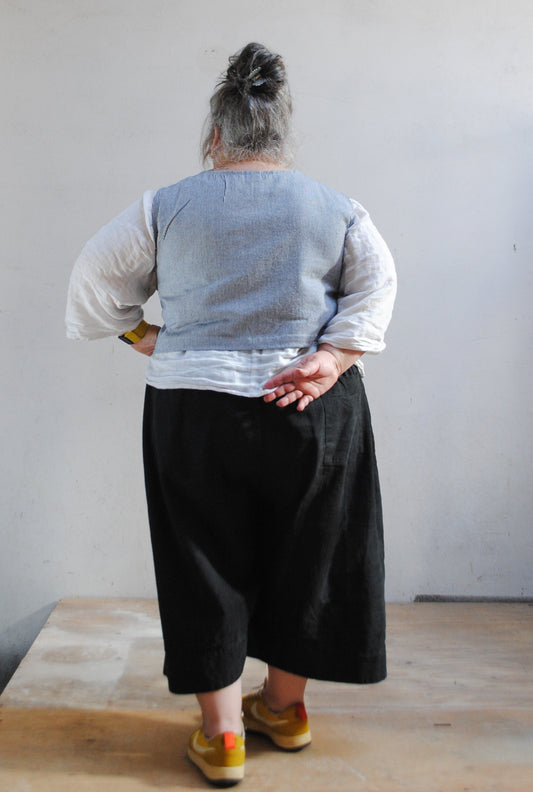 Model wearing crop railroad denim vest in size 2XL with 52" bust. Back view. 