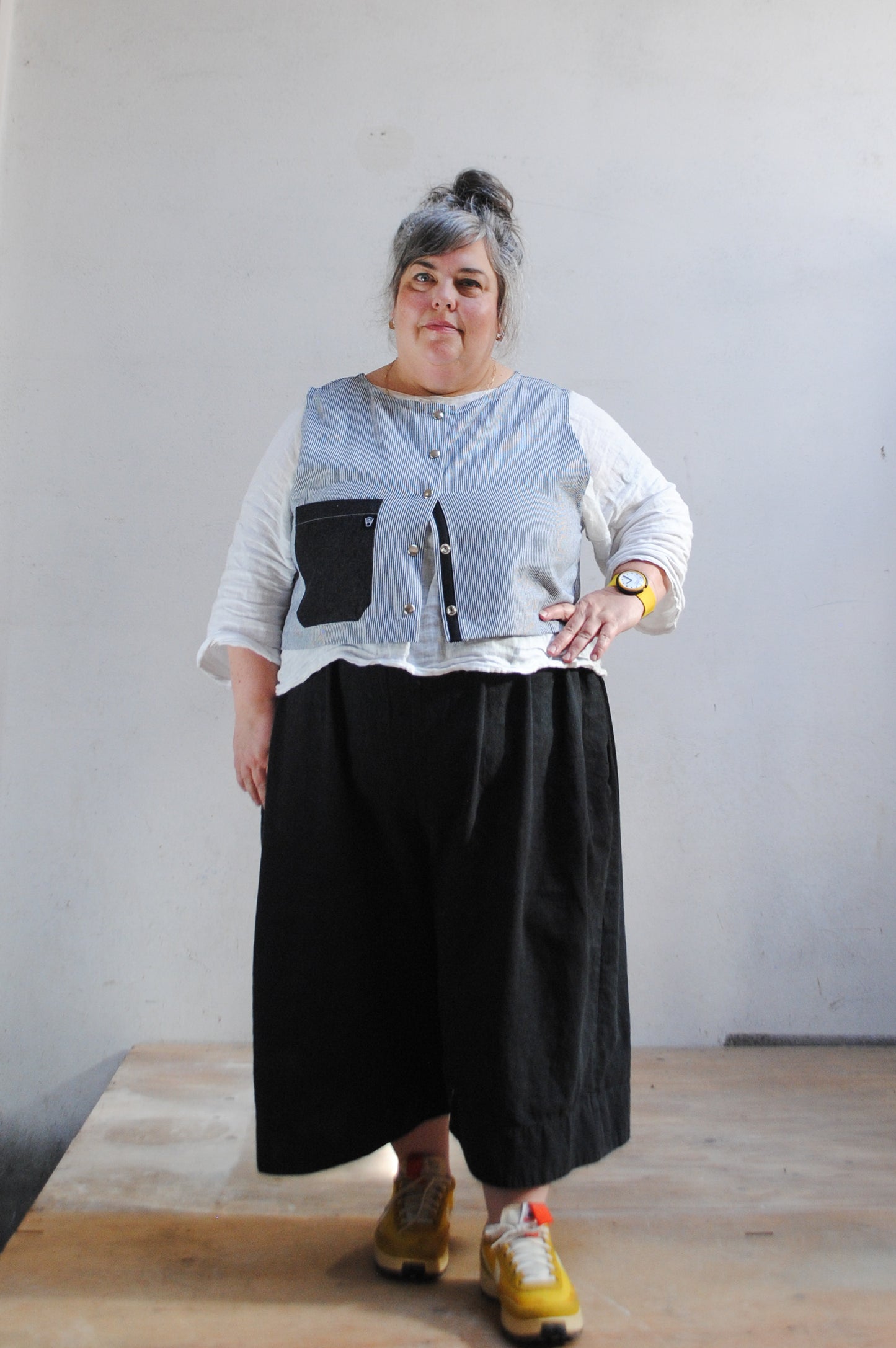 Crop railroad denim vest worn partially open over white linen shirt, showing boxy fit