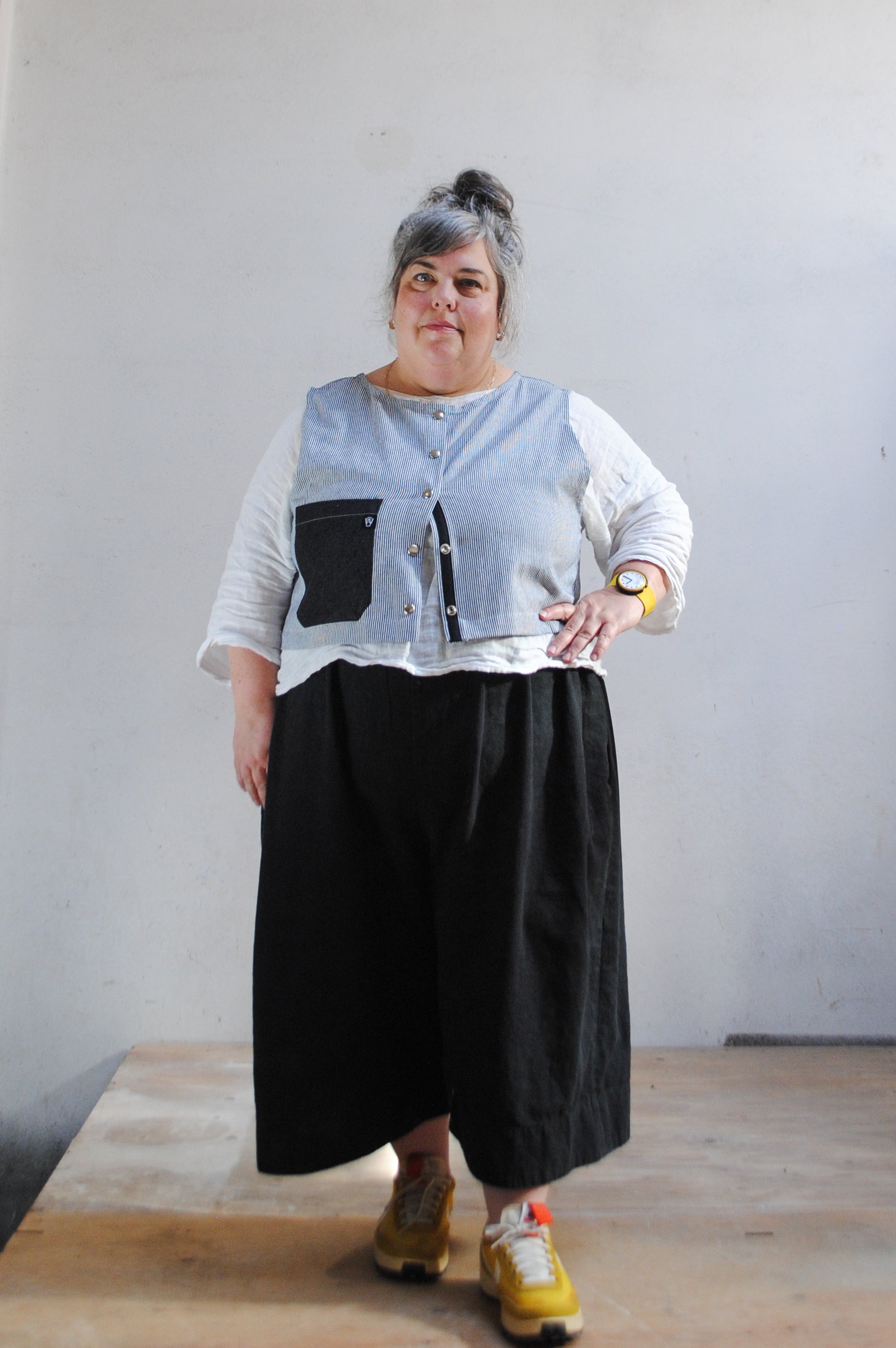 Crop railroad denim vest worn partially open over white linen shirt, showing boxy fit