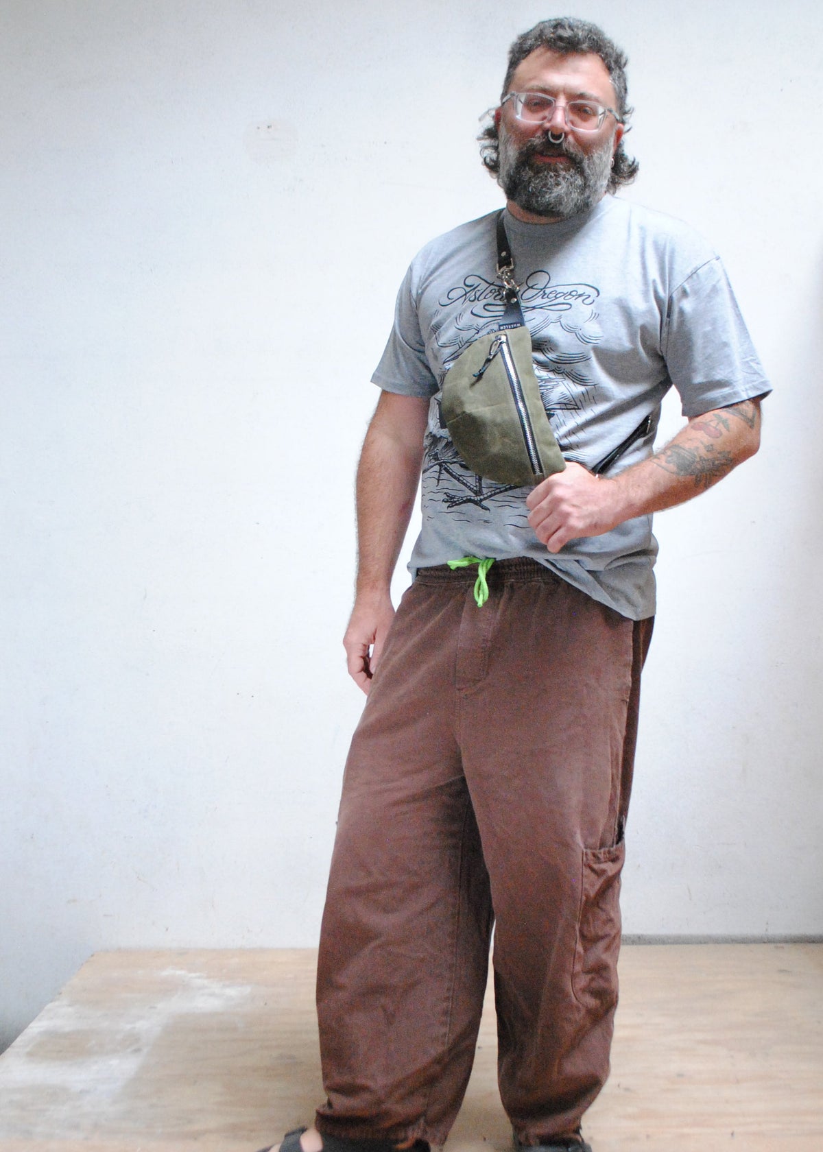 Model wearing handmade olive color waxed canvas fanny pack, fanny pack is being worn over the shoulder