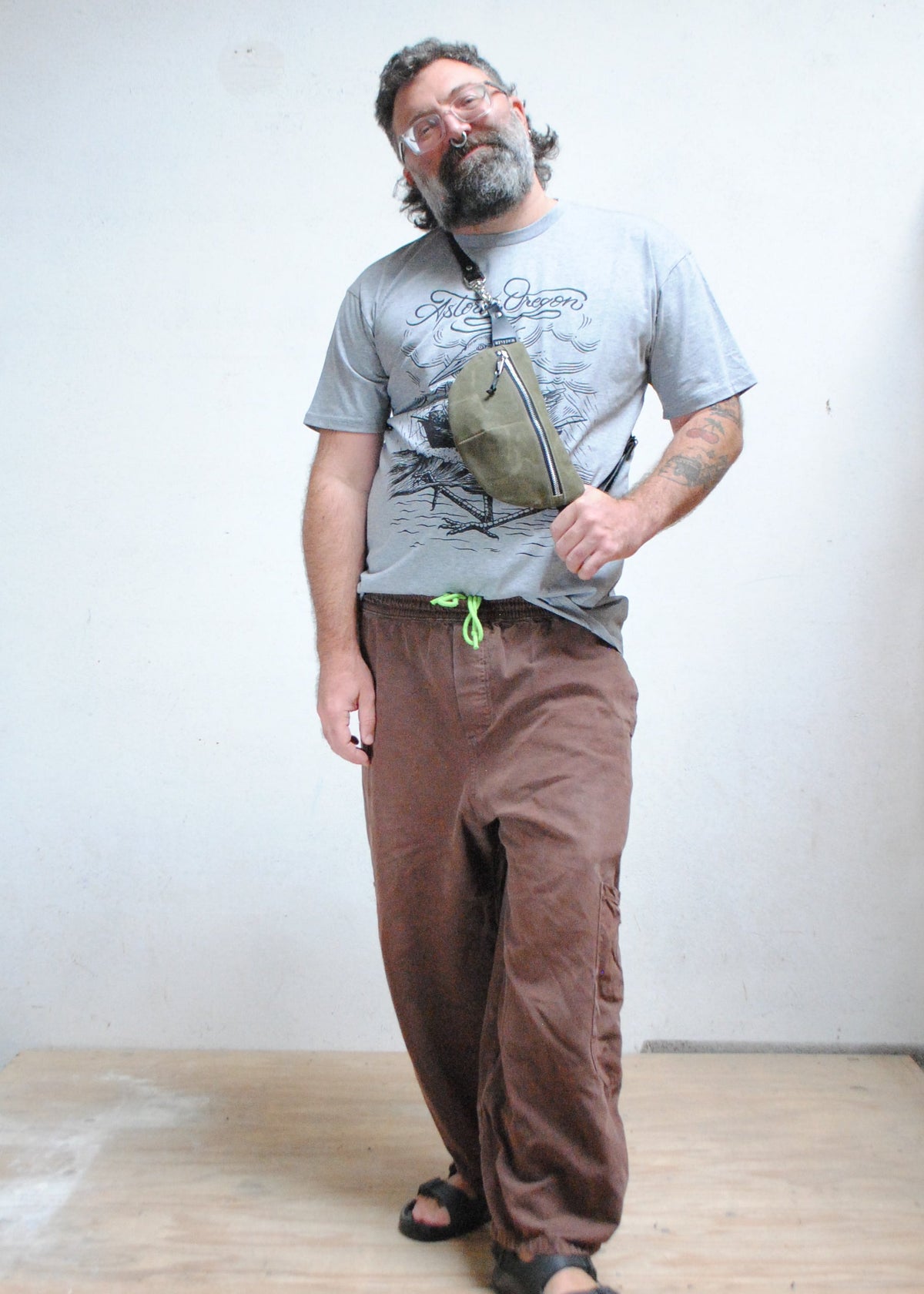 Model wearing handmade olive color waxed canvas fanny pack, fanny pack is being worn over the shoulder