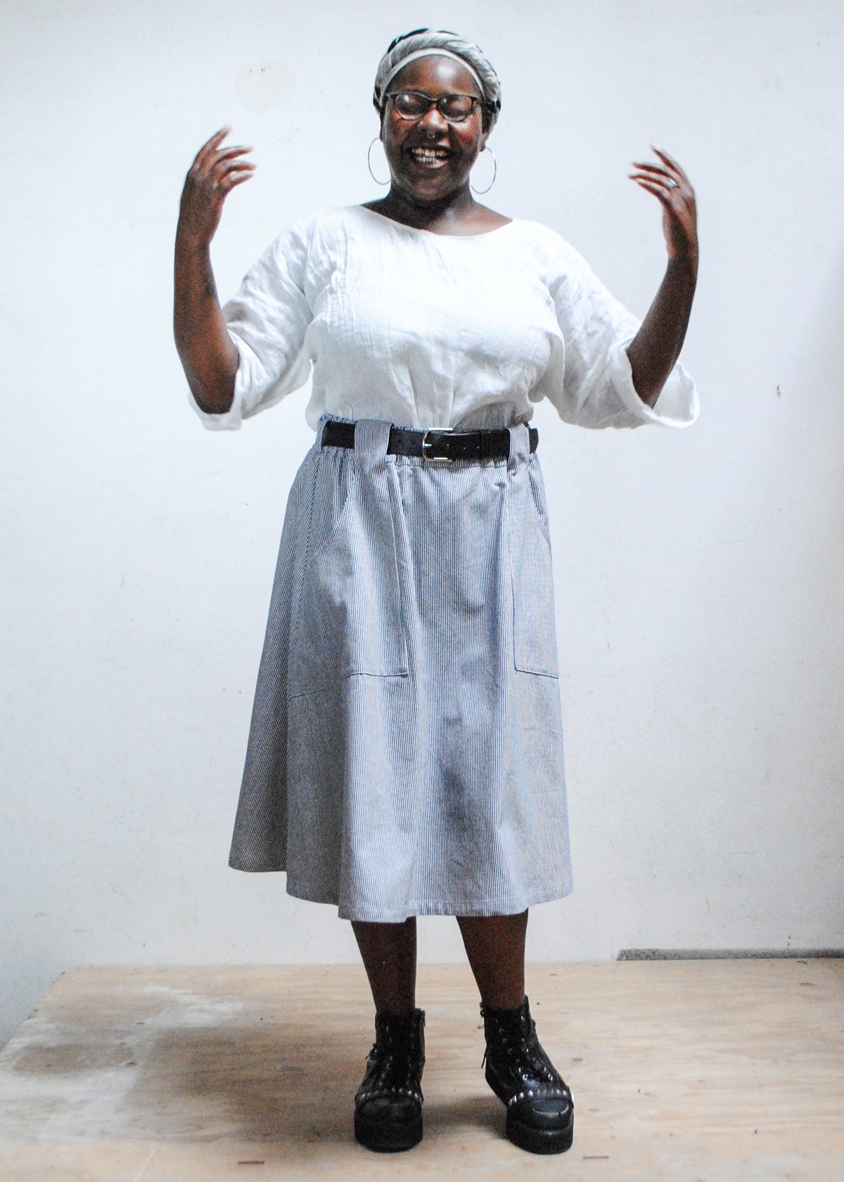Model in white top, black boots, and Shift + Wheeler handmade railroad stripe skirt