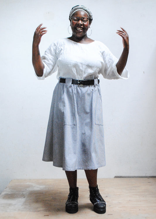 Model in white top, black boots, and Shift + Wheeler handmade railroad stripe skirt