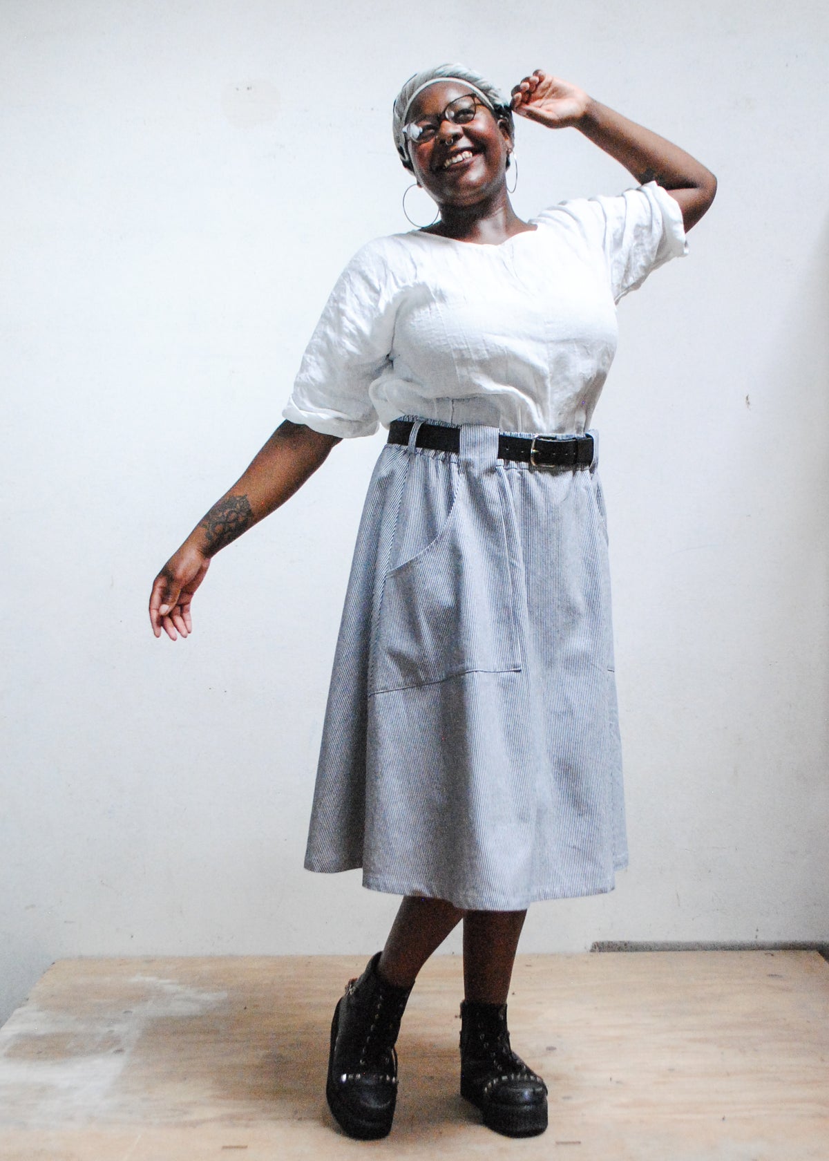 Model in white top, black boots, and Shift + Wheeler handmade railroad stripe skirt