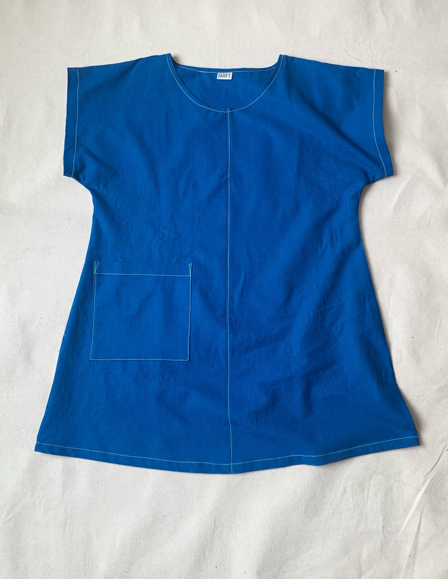 Brightest blue tunic with neon yellow/green topstitching and one big pocket. 55% linen, 45% cotton, medium weight.