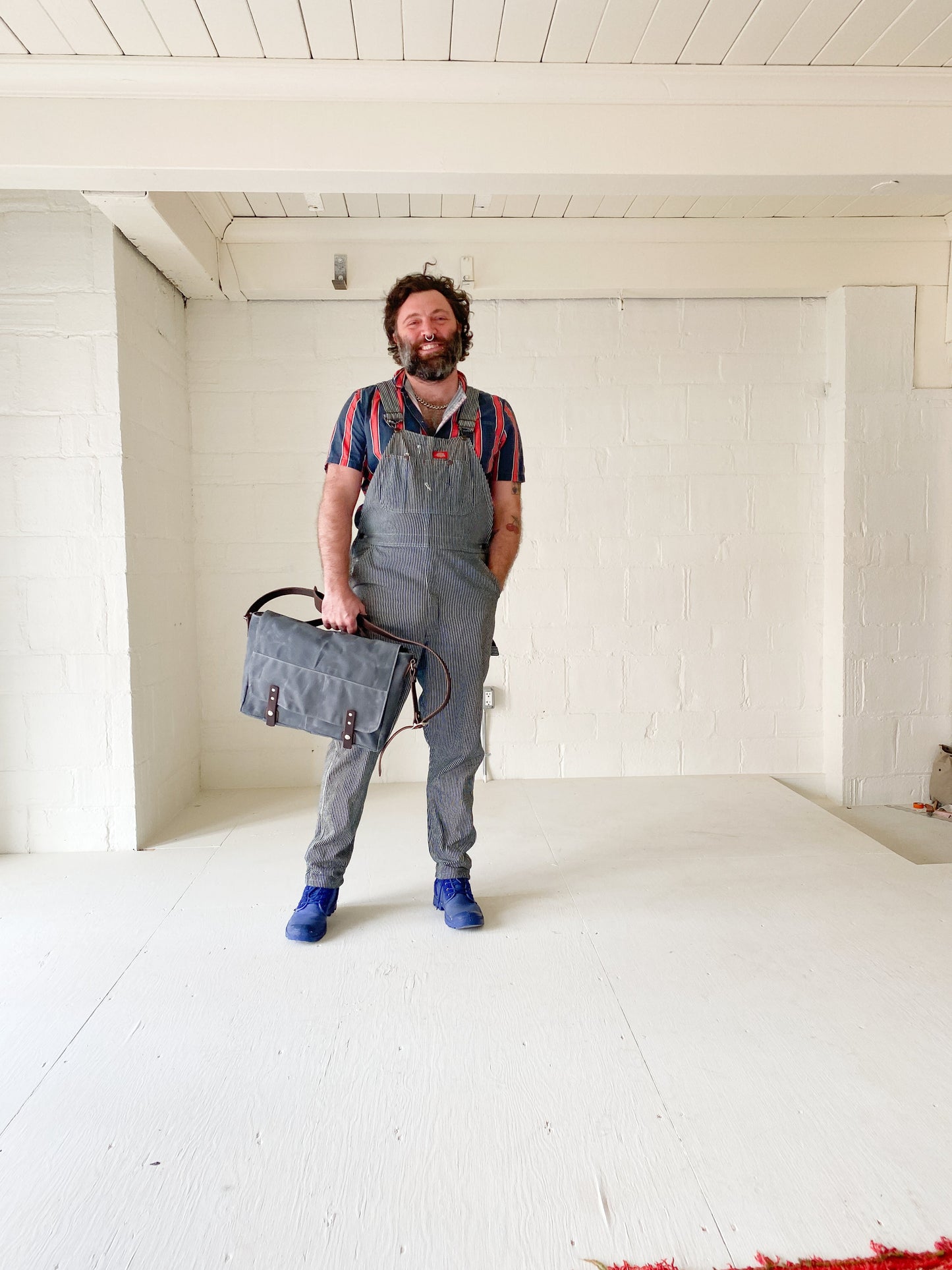 Model holding Slate, waxed canvas messenger bag.