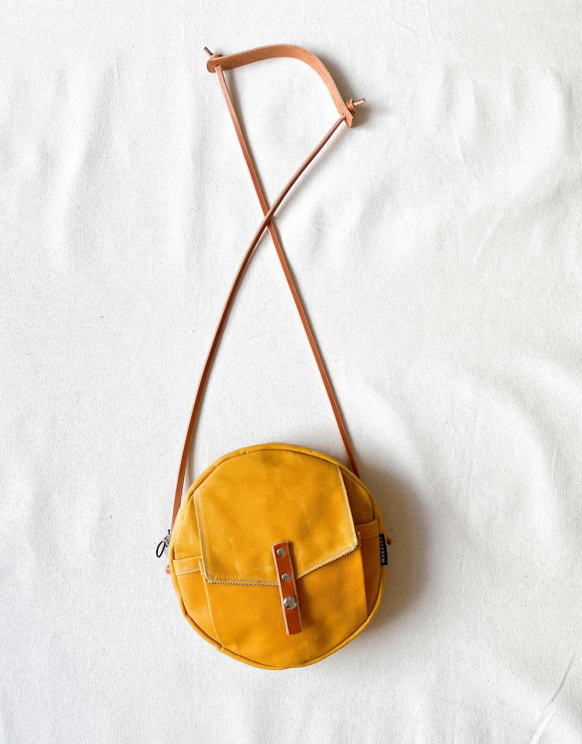 Circle bag with leather straps in yellow.