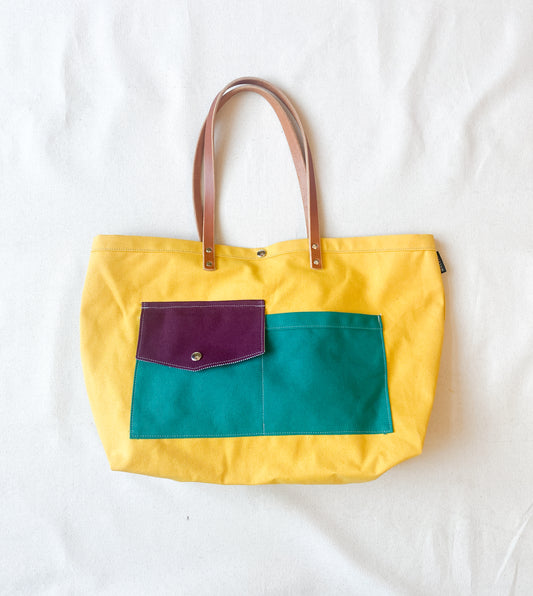 Multi-color (yellow, purple, teal) canvas beach tote with leather straps. 