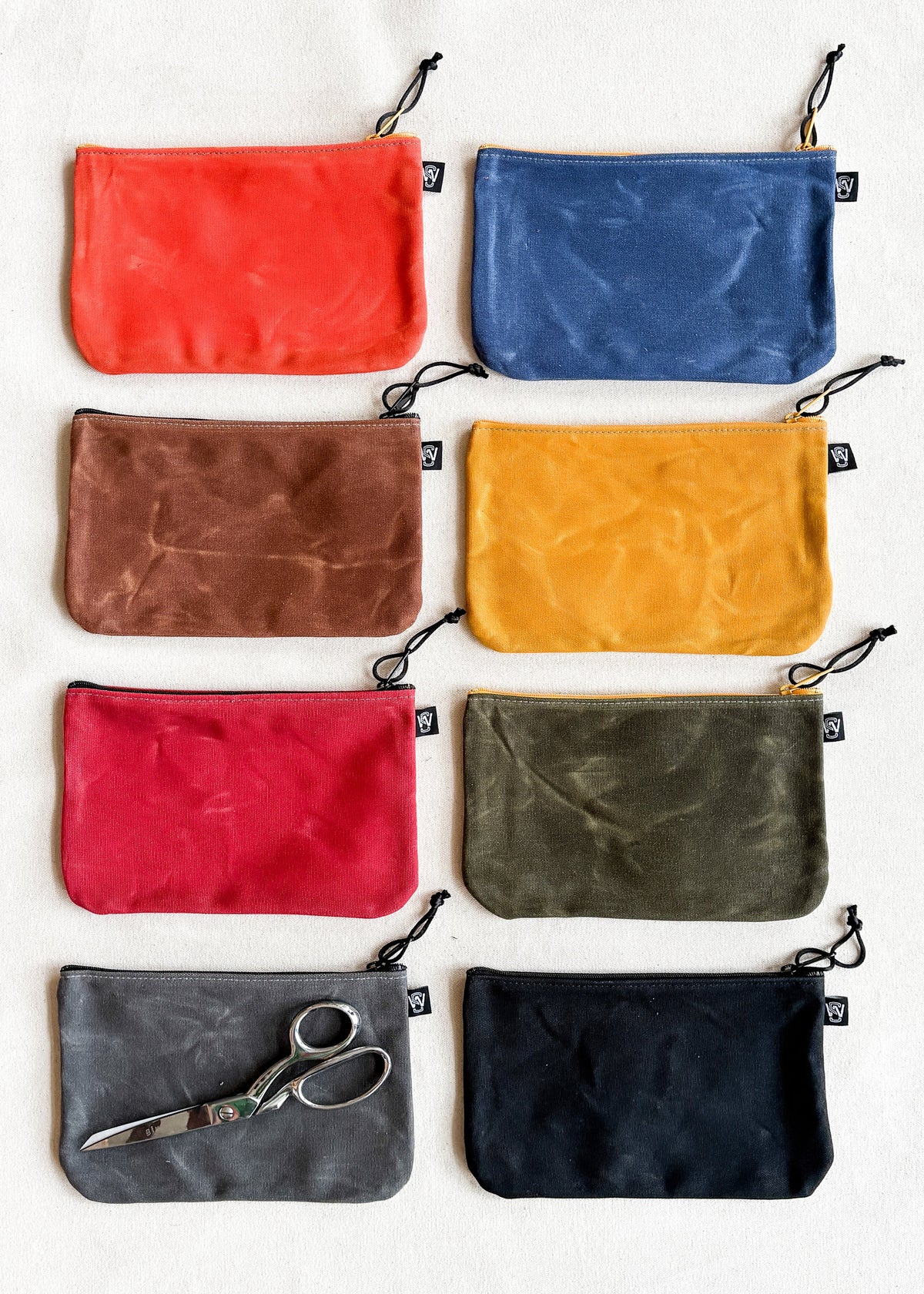 Eight large zipper pouches in a variety of colors, laid flat on a tabletop