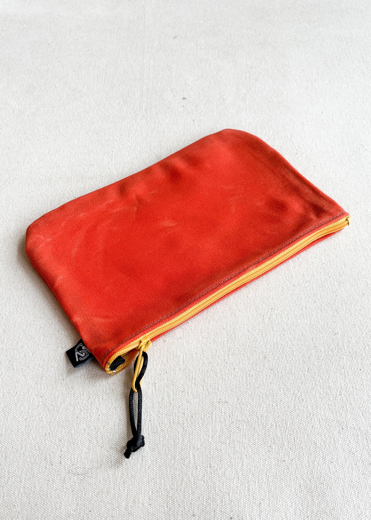 Large waxed canvas zipper pouch in orange with yellow zipper