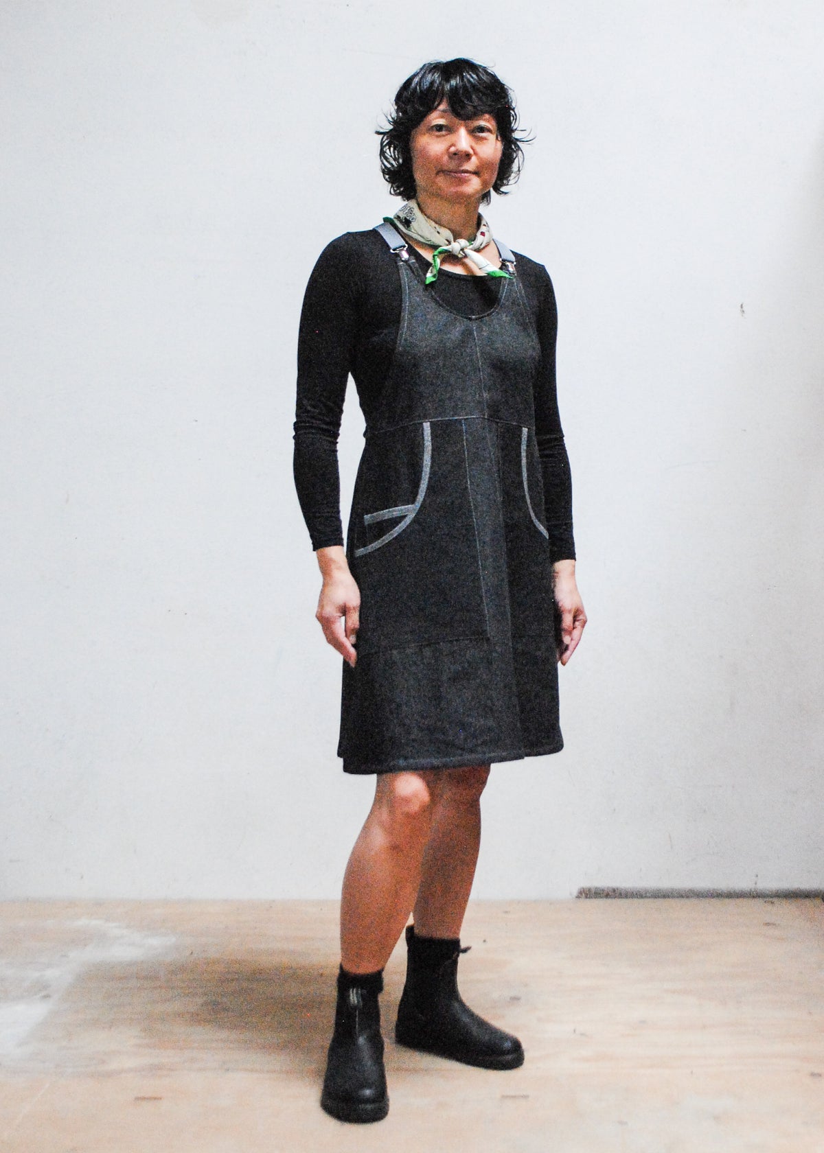 Model wearing handmade black denim suspender dress with grey adjustable suspenders, knee-length pinafore style