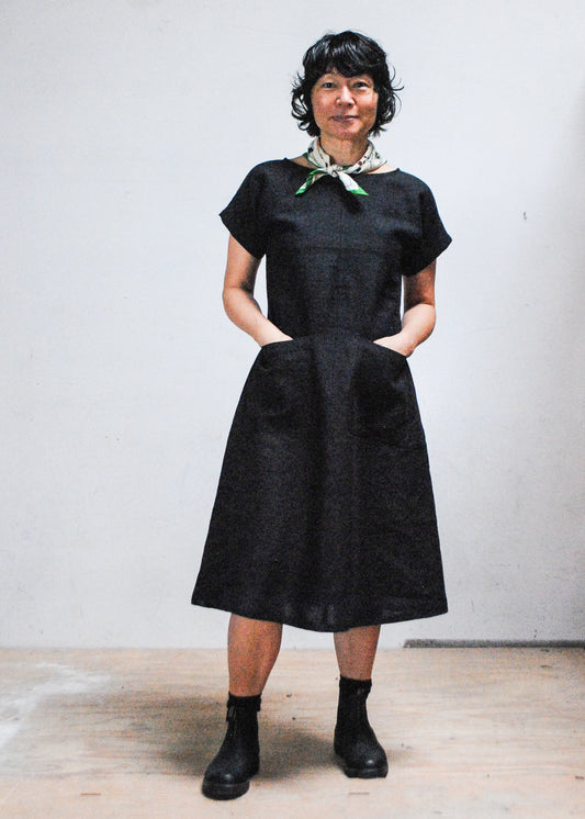 Model wearing handmade black linen dress with hands in front dress pockets