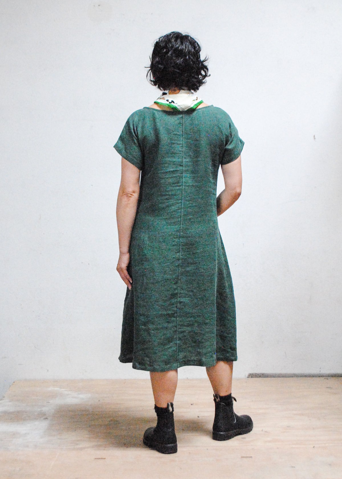 Model with hands in pockets wearing Shift + Wheeler Basic Dress in green linen - back view