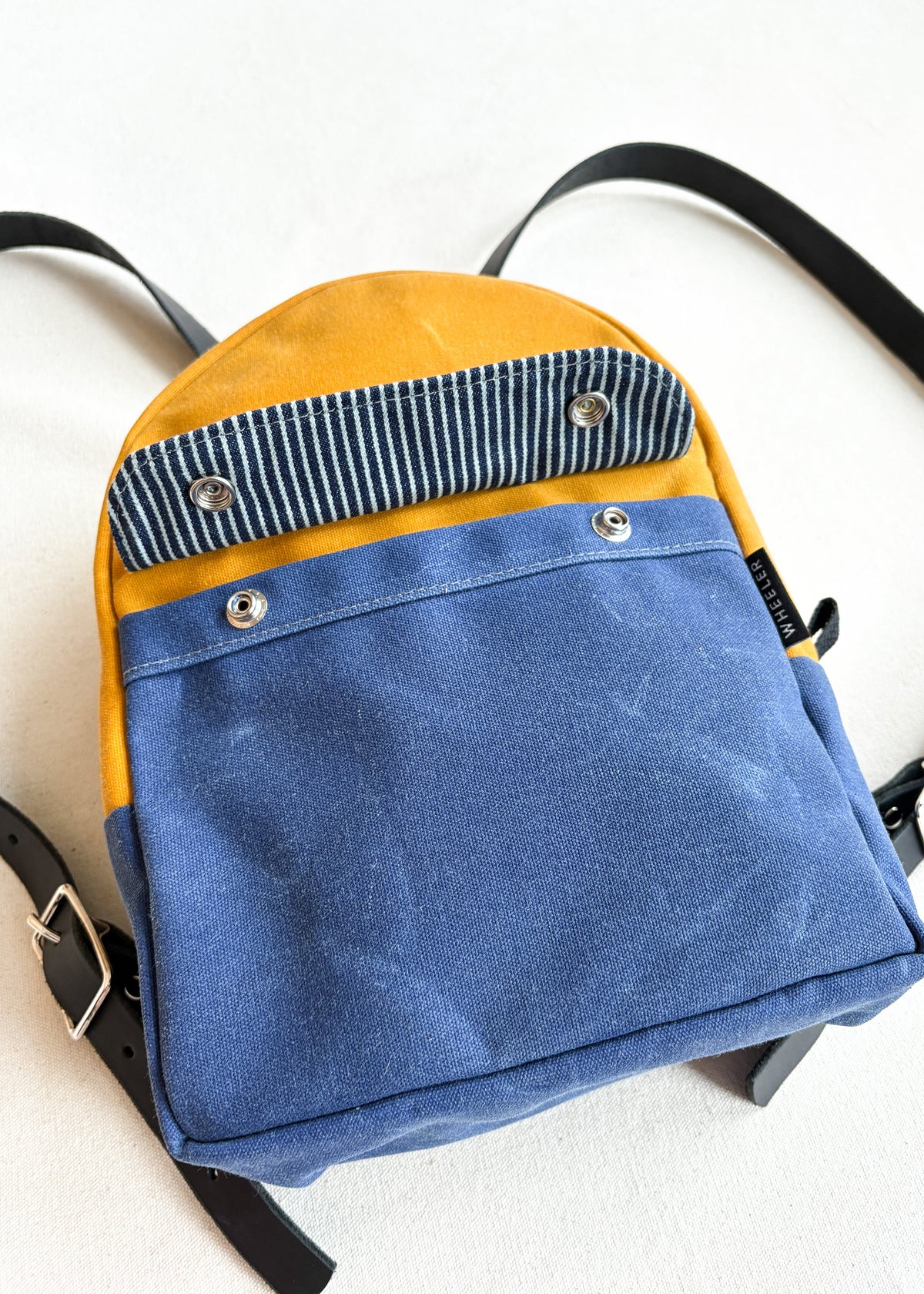 2-tone yellow gold and royal handmade Shift + Wheeler waxed canvas mini backpack - front view details of front snap pocket