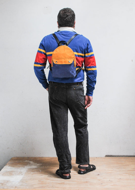 Model wearing 2-tone yellow gold and royal blue handmade Shift + Wheeler waxed canvas mini backpack - back view