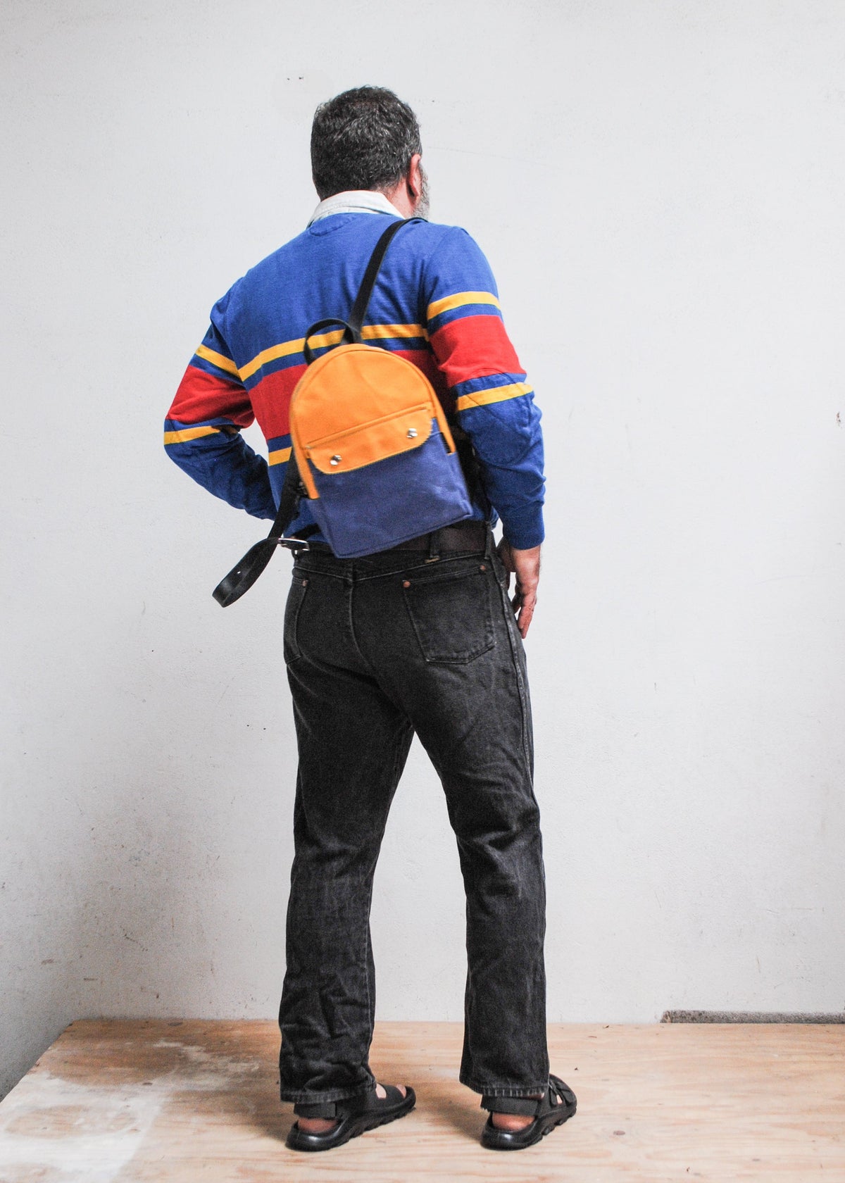 Model wearing 2-tone yellow gold and royal handmade Shift + Wheeler waxed canvas mini backpack on one shoulder - back view
