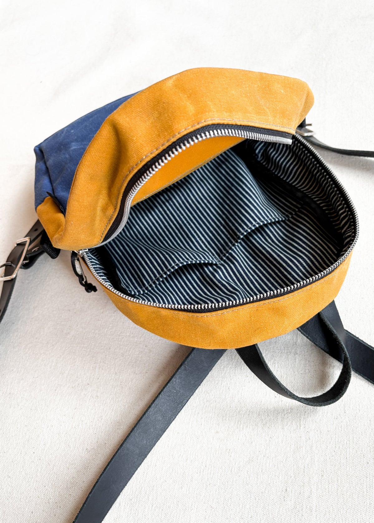 2-tone yellow gold and royal blue handmade Shift + Wheeler waxed canvas mini backpack, open top view of inside bag