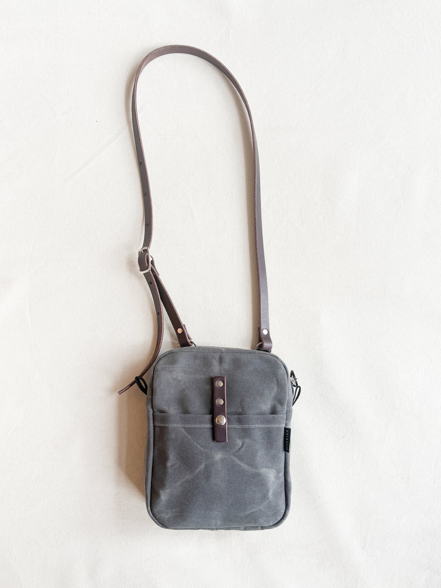Exterior snap pocket on waxed canvas mini messenger bag by Shift + Wheeler