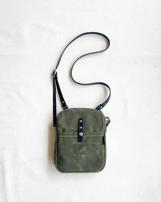 Waxed Canvas Mini Messenger bag in olive canvas with a black leather crossbody strap. 