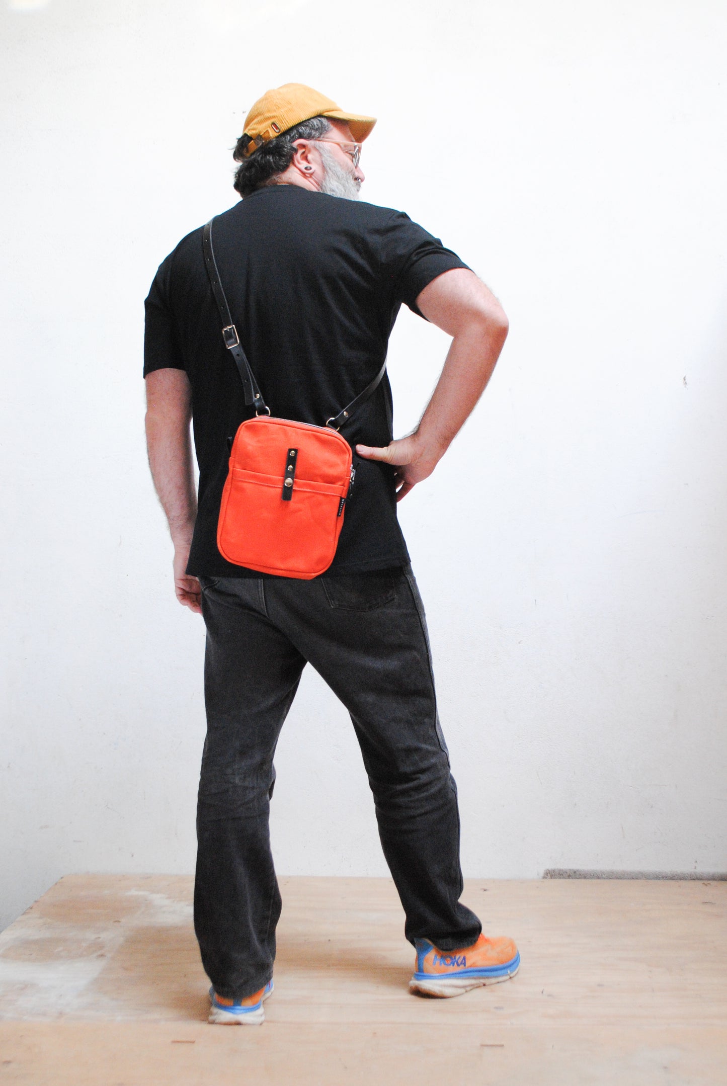 Rear view, waxed canvas mini messenger in orange. 