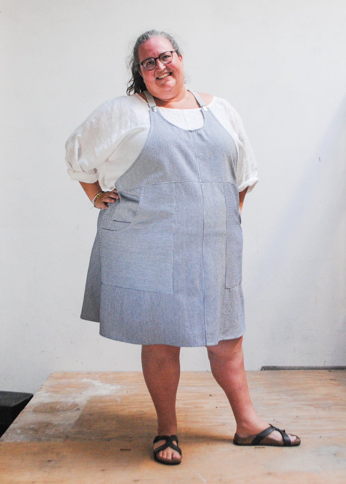 Model wearing handmade railroad stripe suspender dress with hand on hip