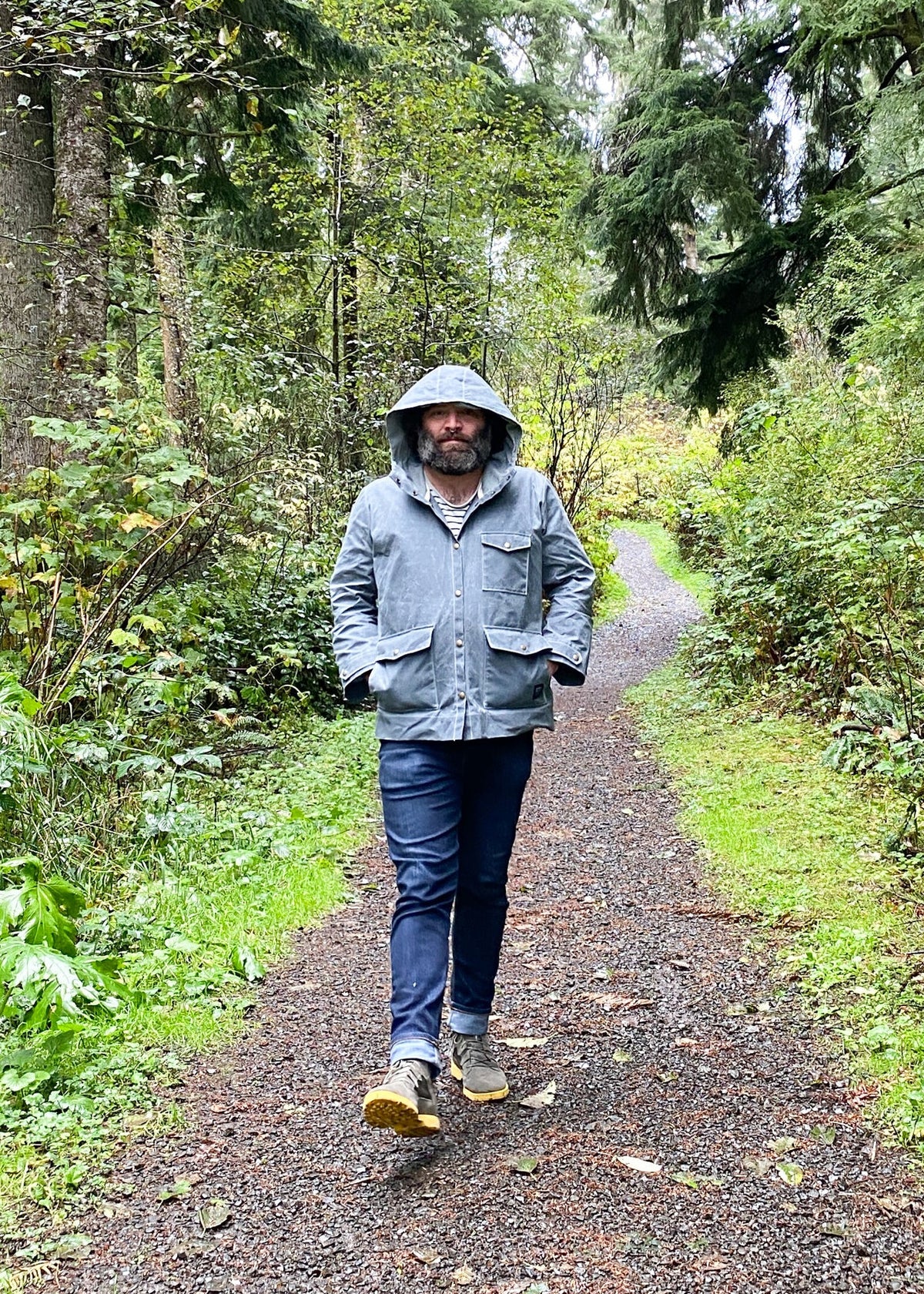 Model wearing Waxed Canvas Raincoat in Slate with hood up.