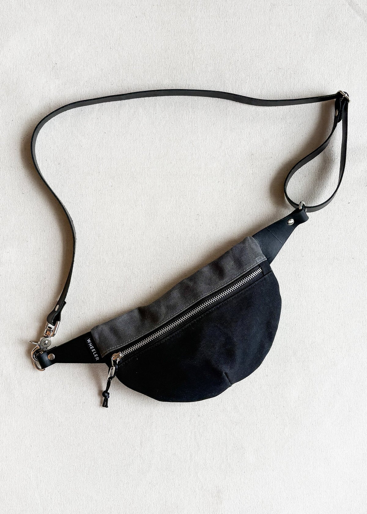 Handmade waxed canvas fanny pack in two-tone (black and charcoal) with black leather strap