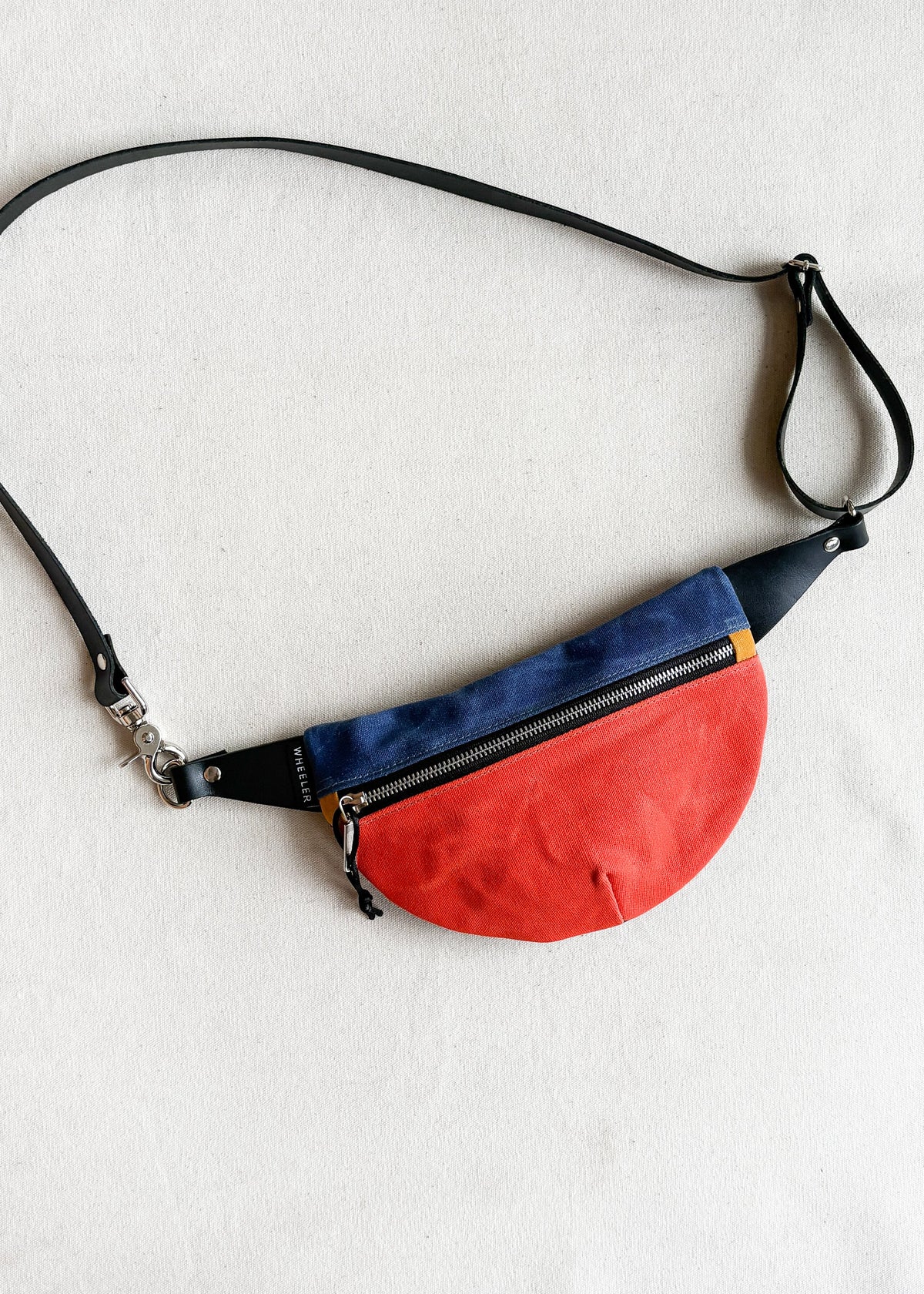 Handmade waxed canvas fanny pack in two-tone (orange and royal blue) with black leather strap