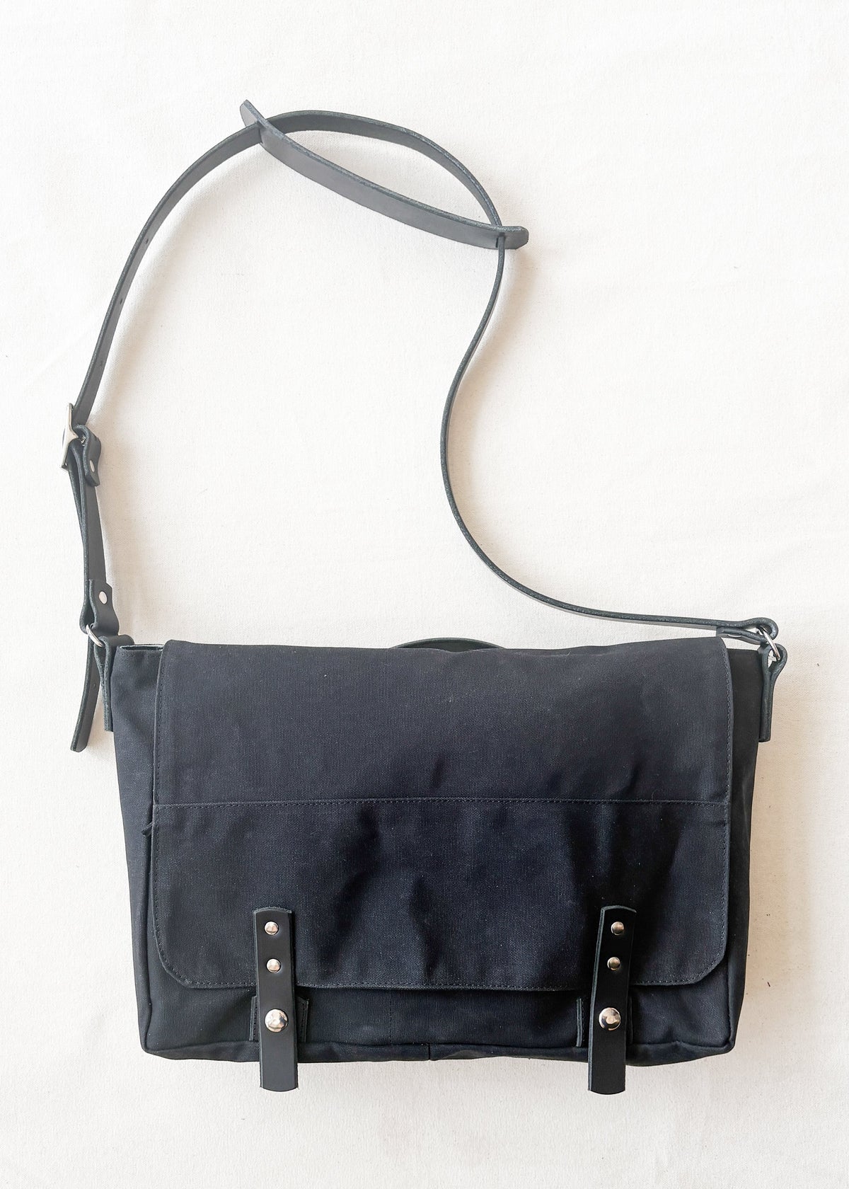Black waxed canvas messenger bag with black leather straps