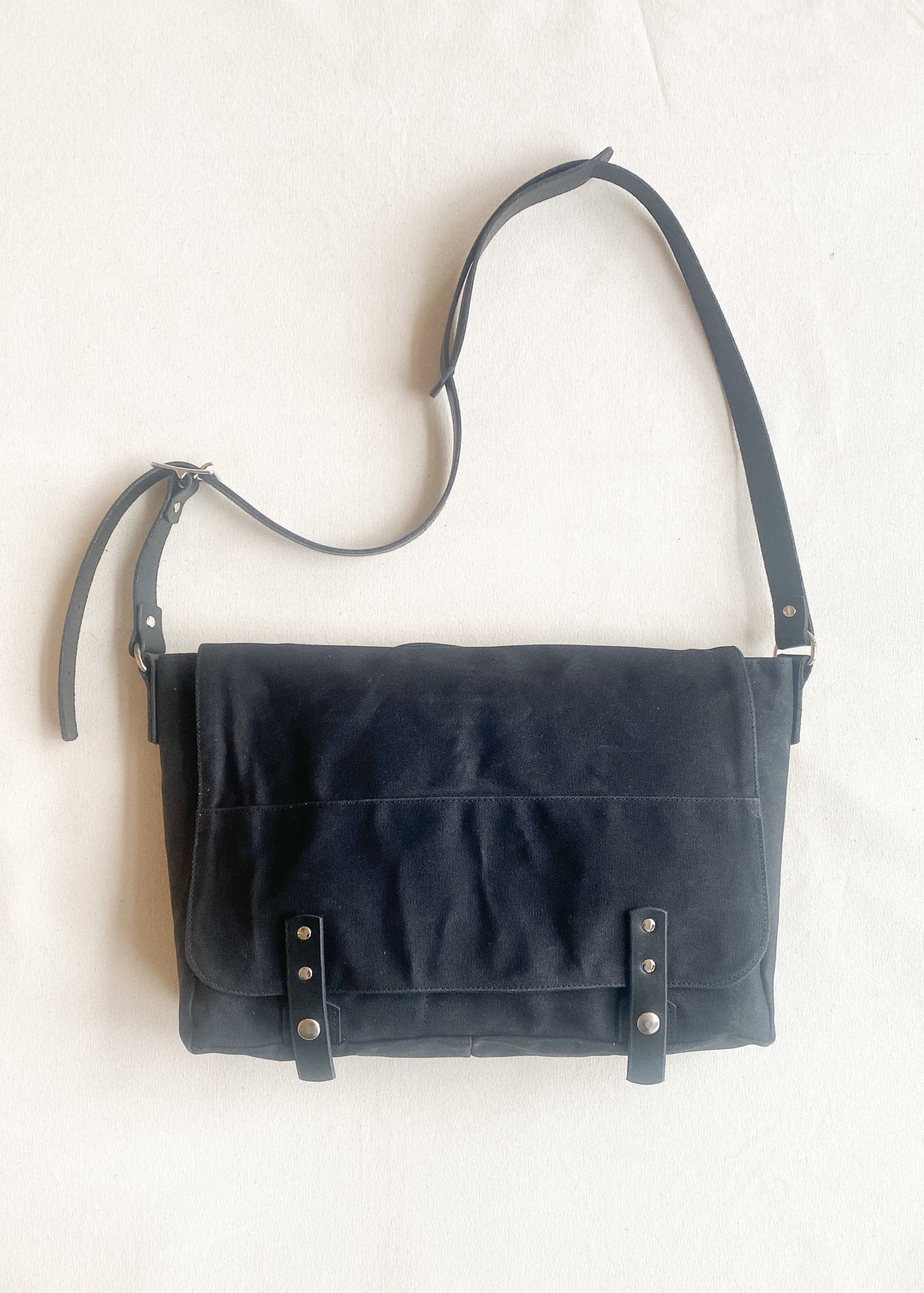 Waxed canvas messenger bag in black with black leather strapping