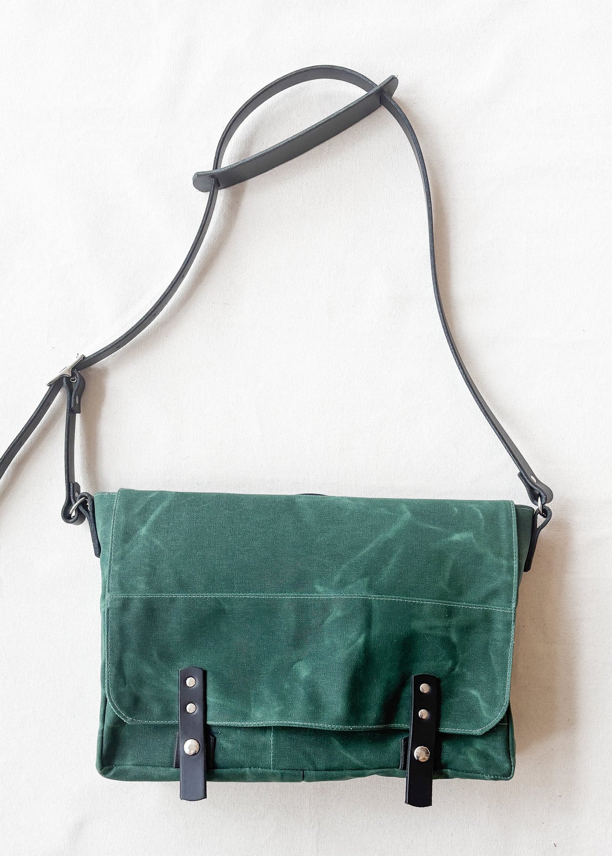 Hunter green waxed canvas messenger bag with black leather straps